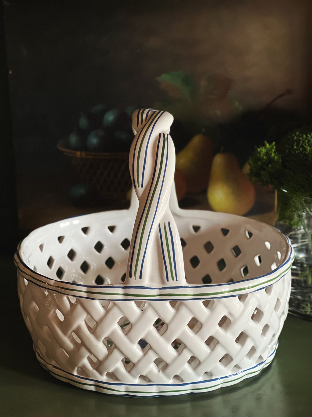 White ceramic basket with a hand painted handle on a dark background