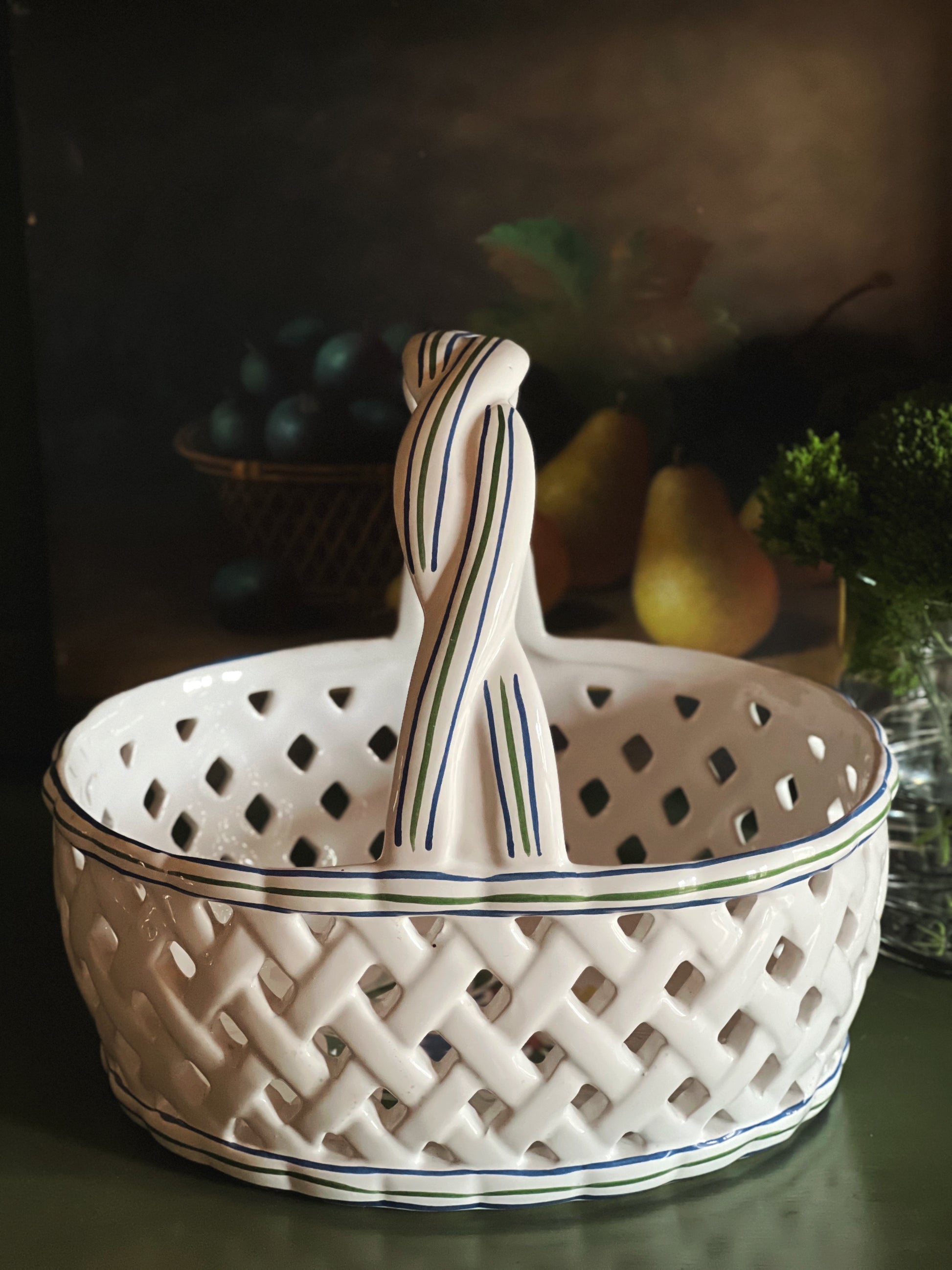 White ceramic basket with a hand painted handle on a dark background