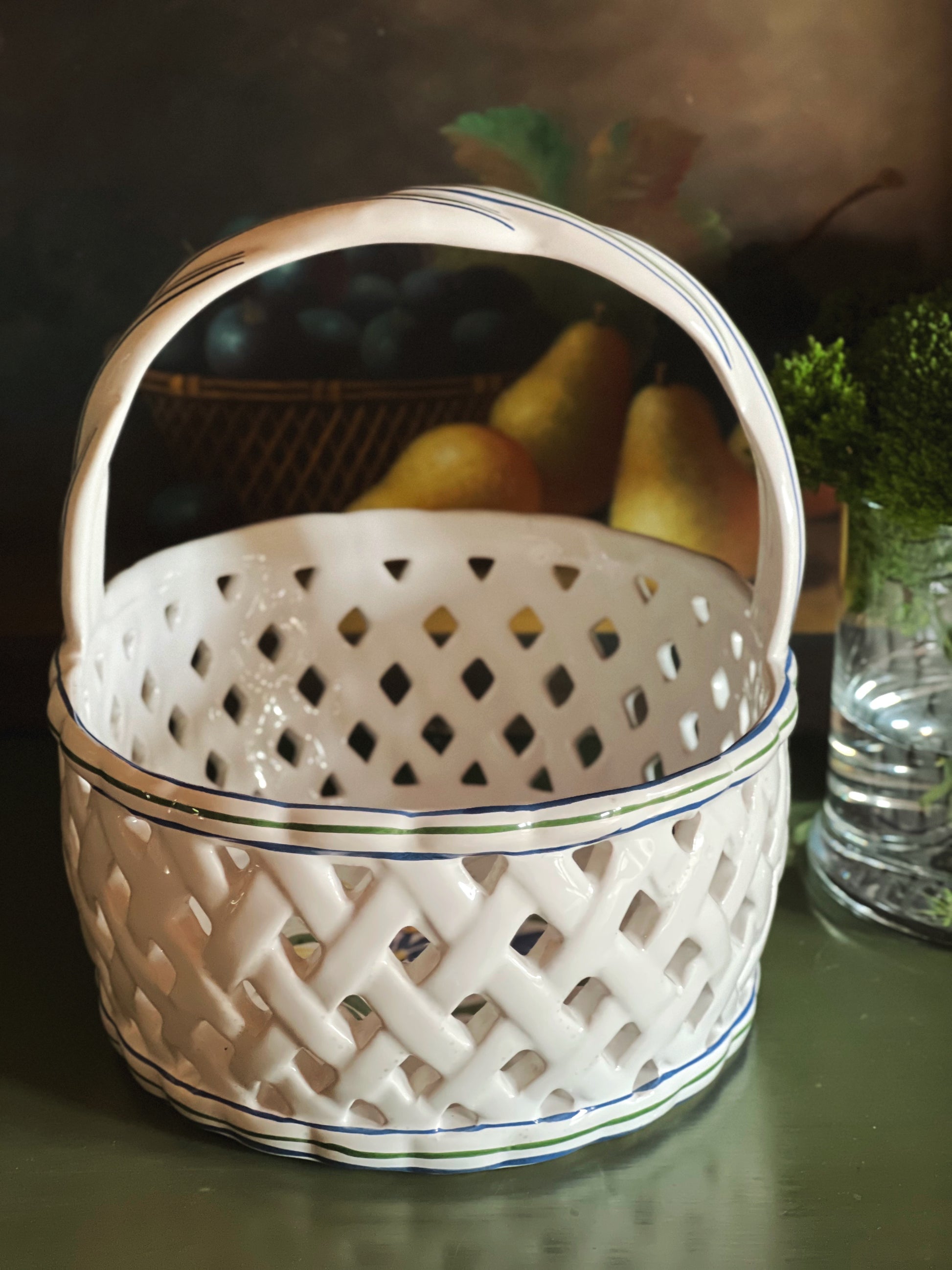 Side view of a white woven ceramic  basket with a handle 
