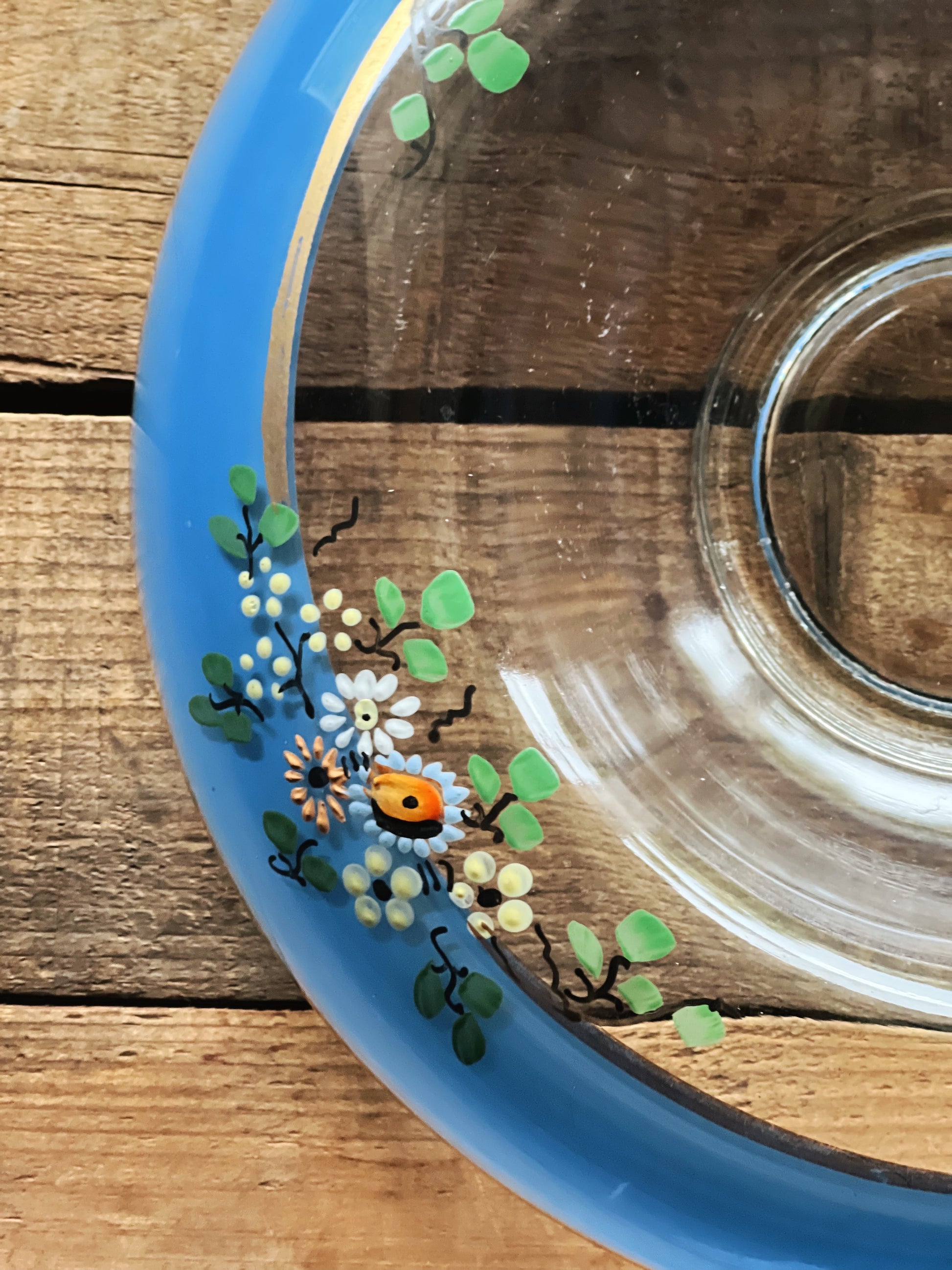 Clear glass dish with blue rim featuring floral design on a wooden surface