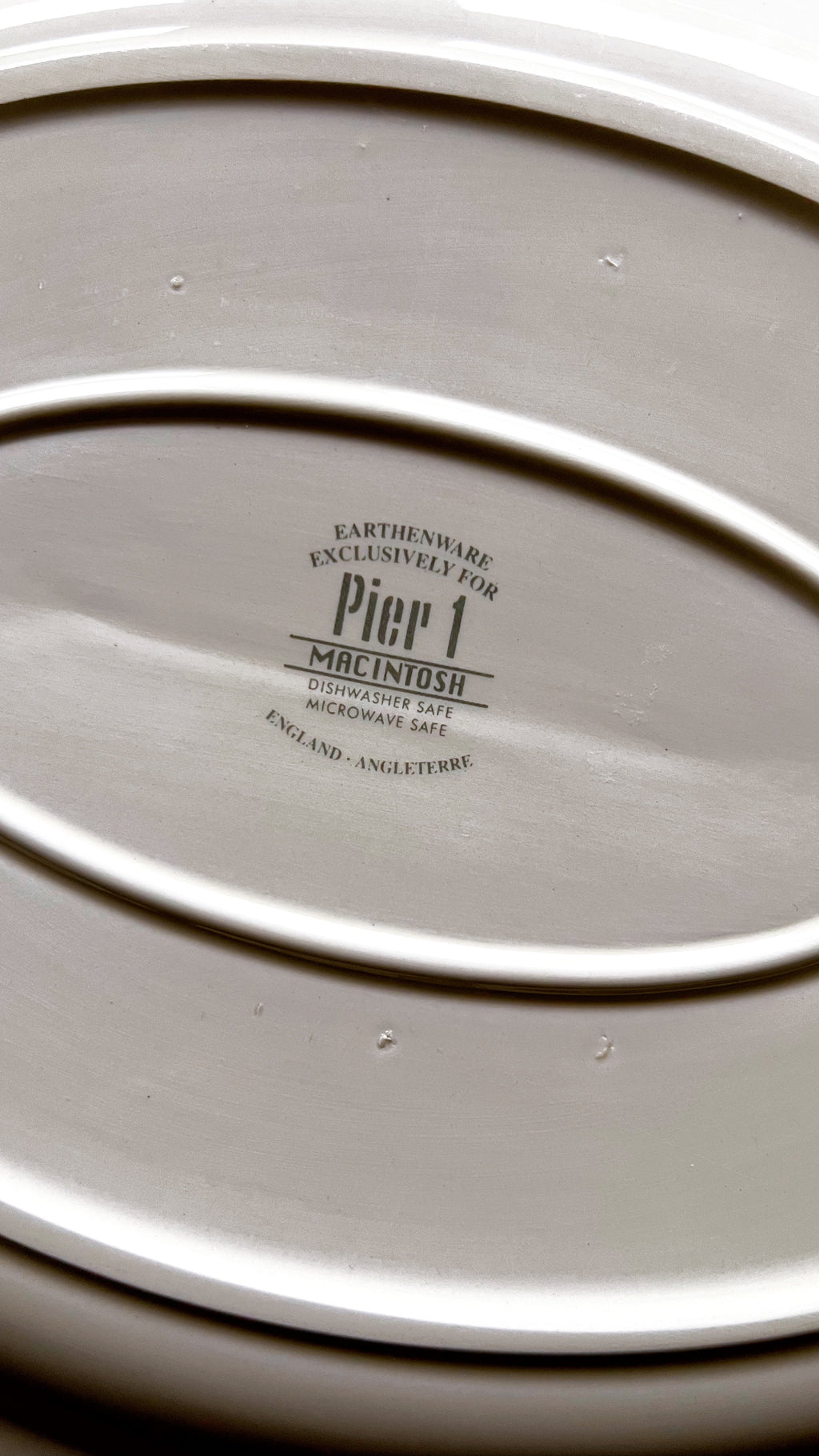 Close-up of a ceramic platter with 'Pier 1' branding on a dark background