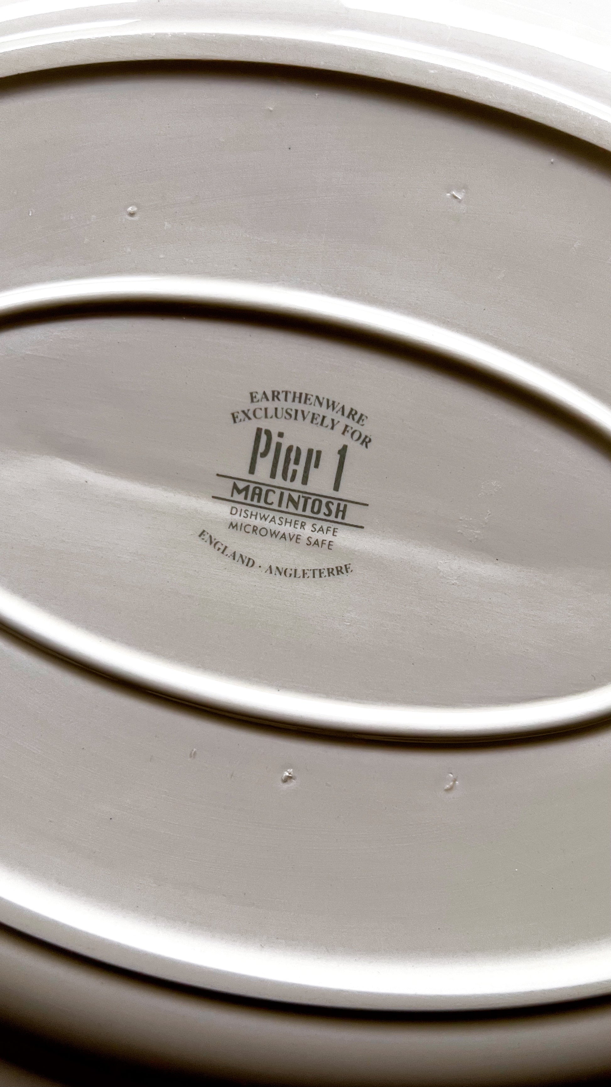 Close-up of a ceramic platter with 'Pier 1' branding on a dark background