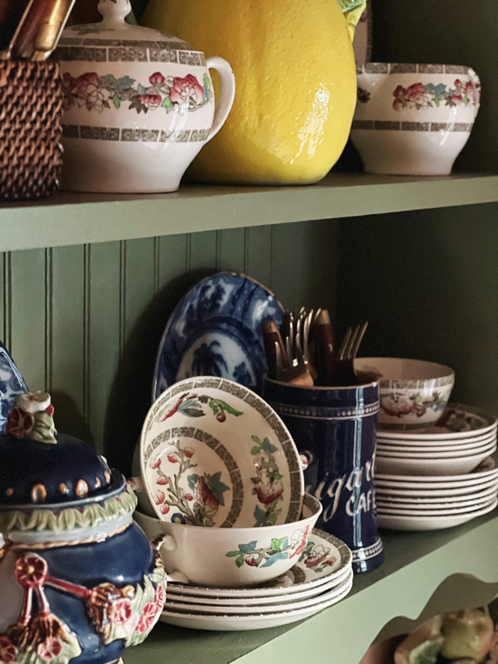 Floral English transferware two-handle bouillon bowls stacked beside blue vintage canister