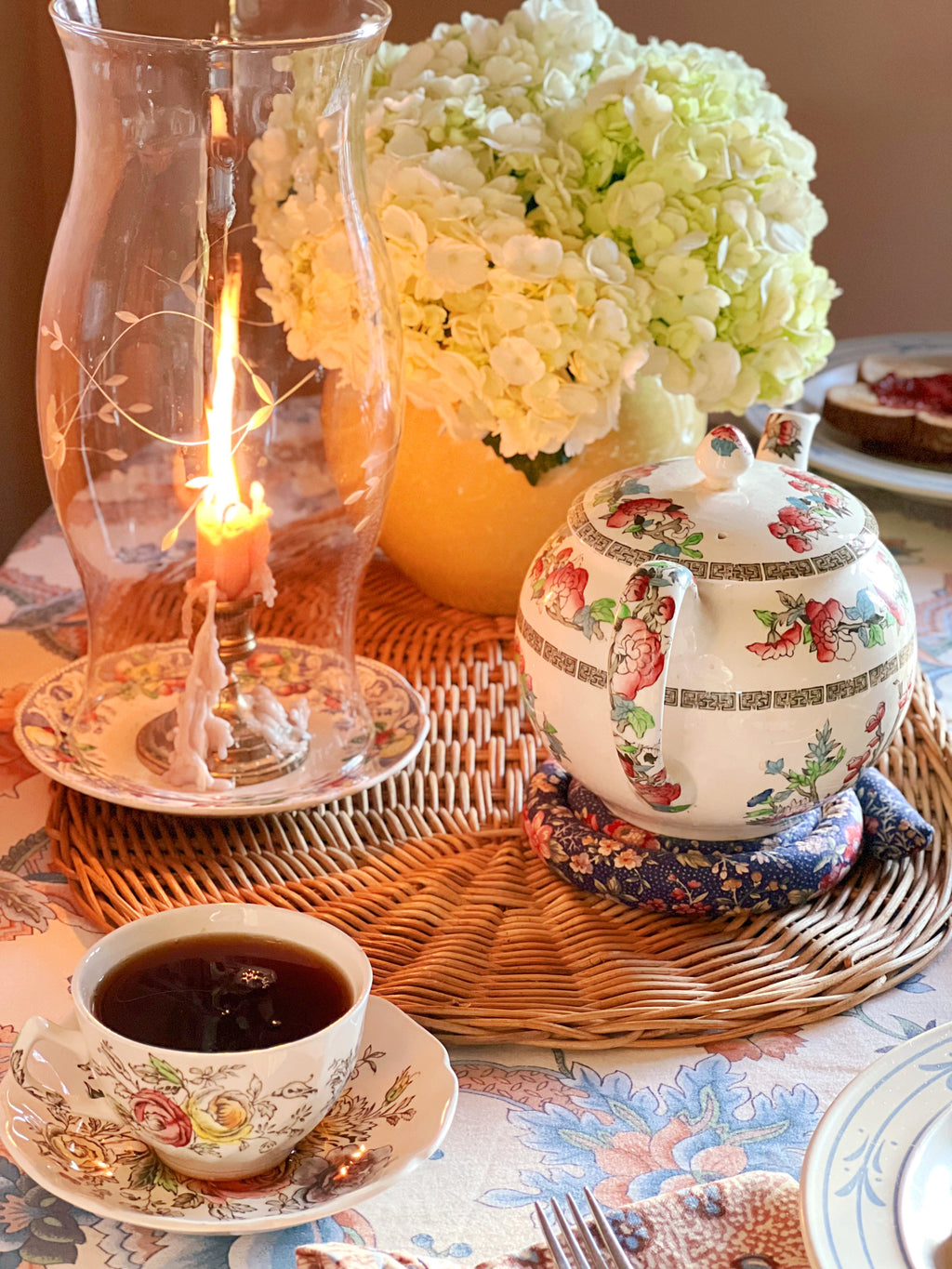 Vintage Royal Doulton Pomeroy Blue saucer styled beneath a glass hurricane candle on a layered breakfast table