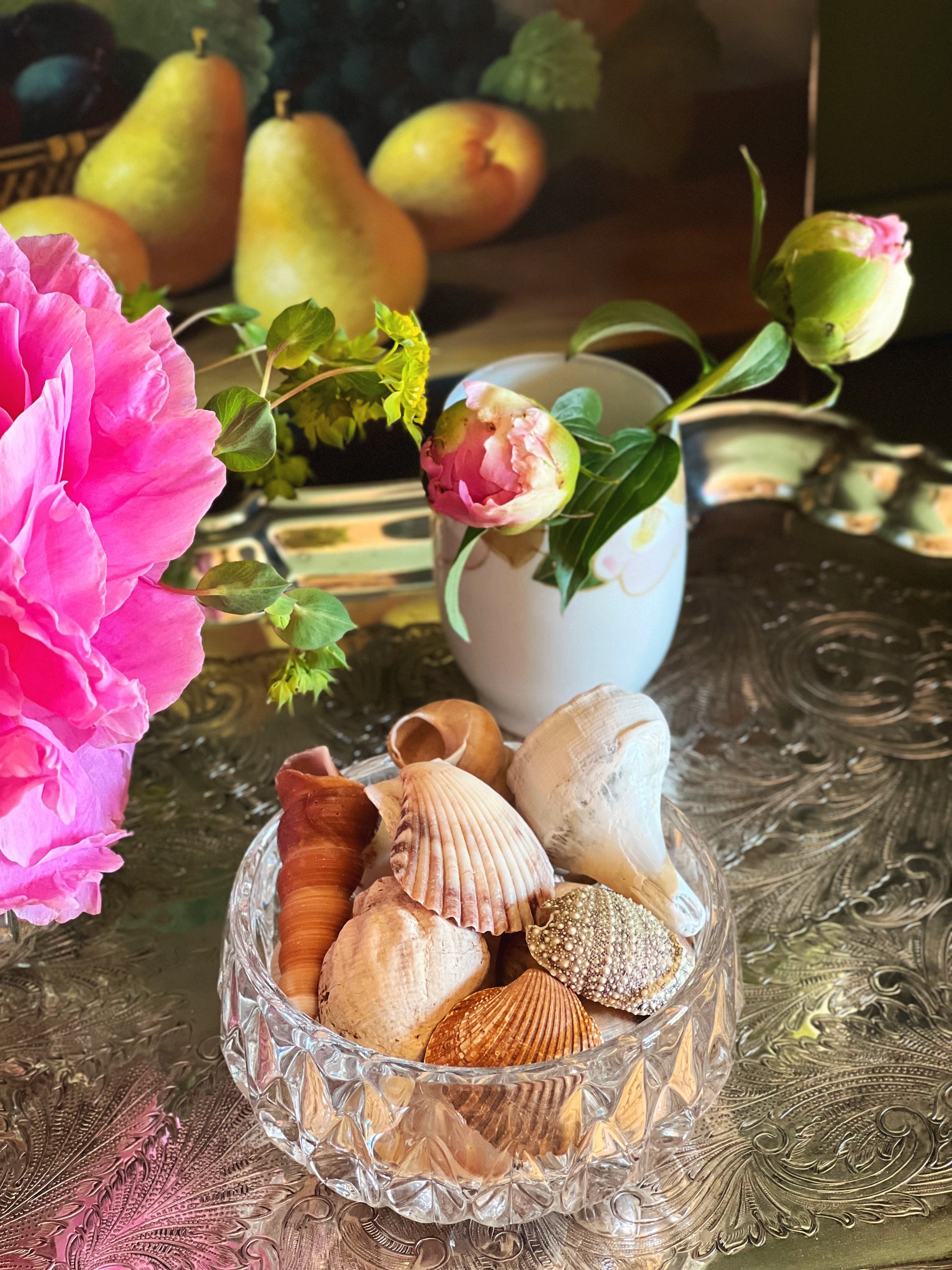 Vintage crystal bowl with seashells on a decorative table with flowers and fruit