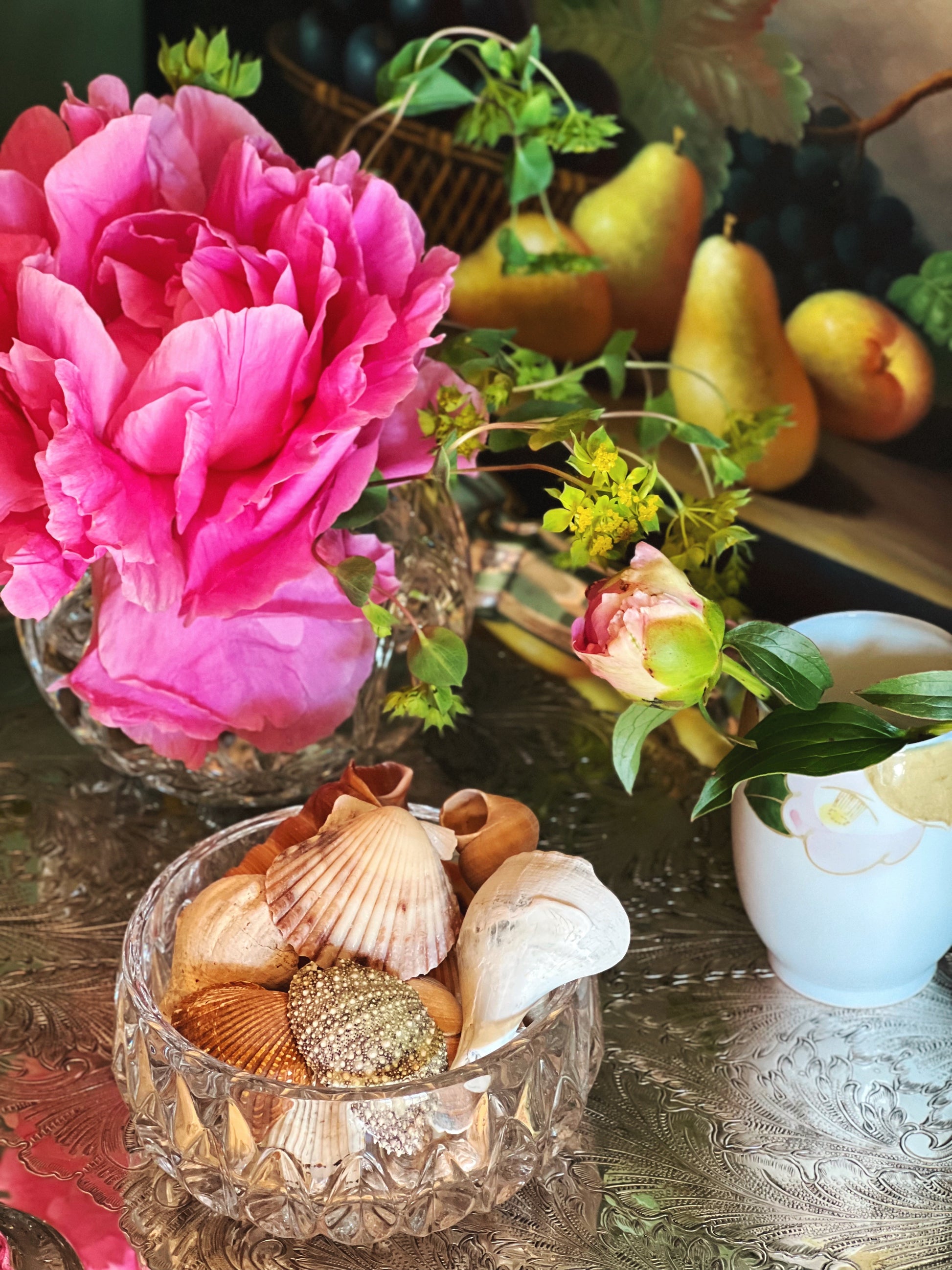 Small crystal bowl filled with shells on a silver tray with flowers