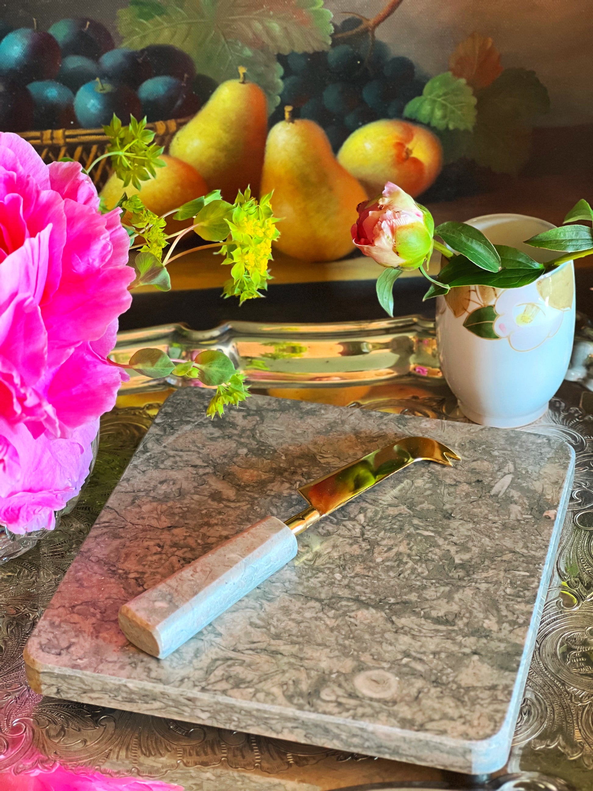 Marble cutting board with knife on a table with fruit and flowers