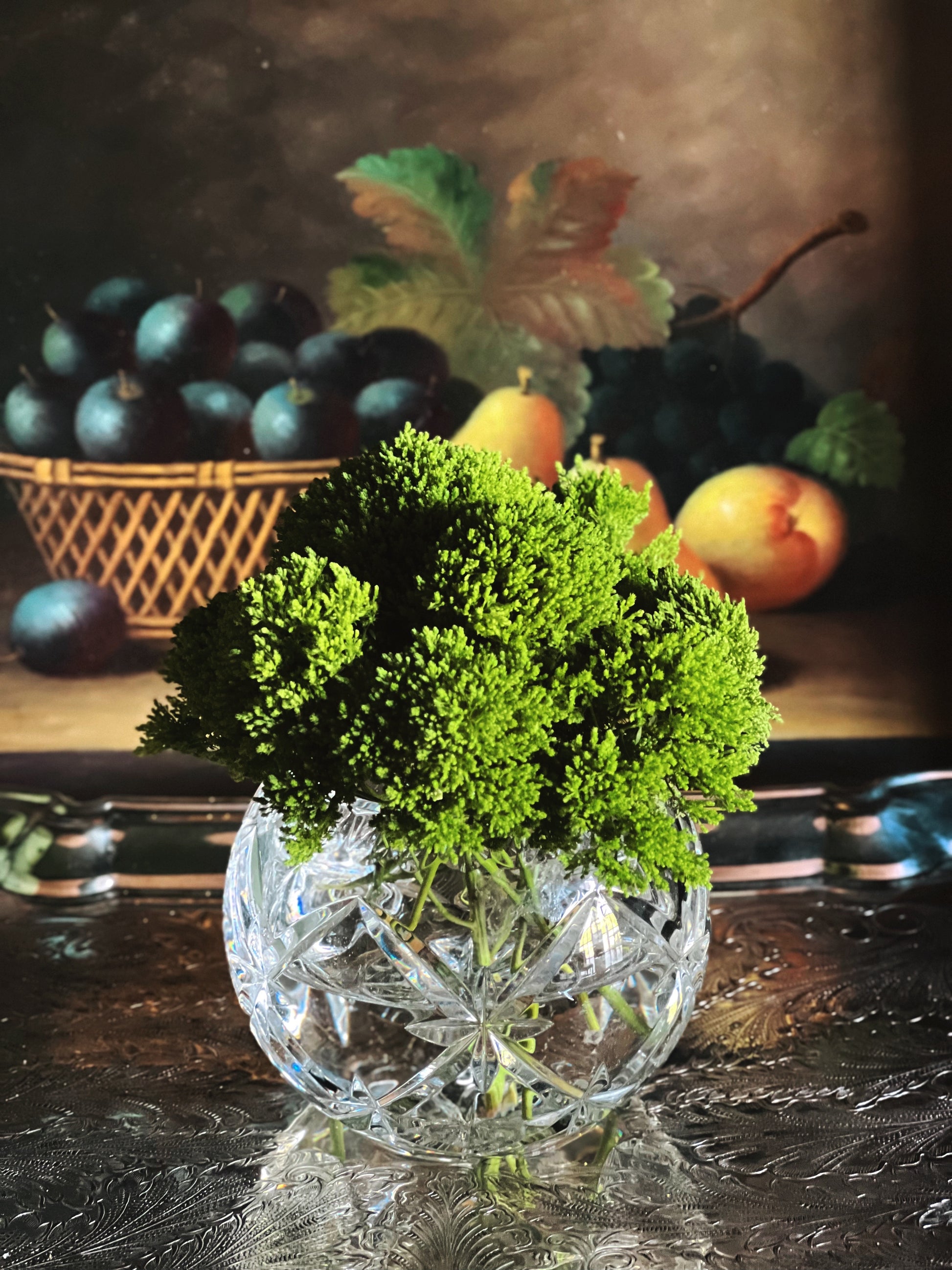 Vintage cut crystal bud vase styled with fresh green florals on a dark tabletop for gathered entertaining and collected home decor