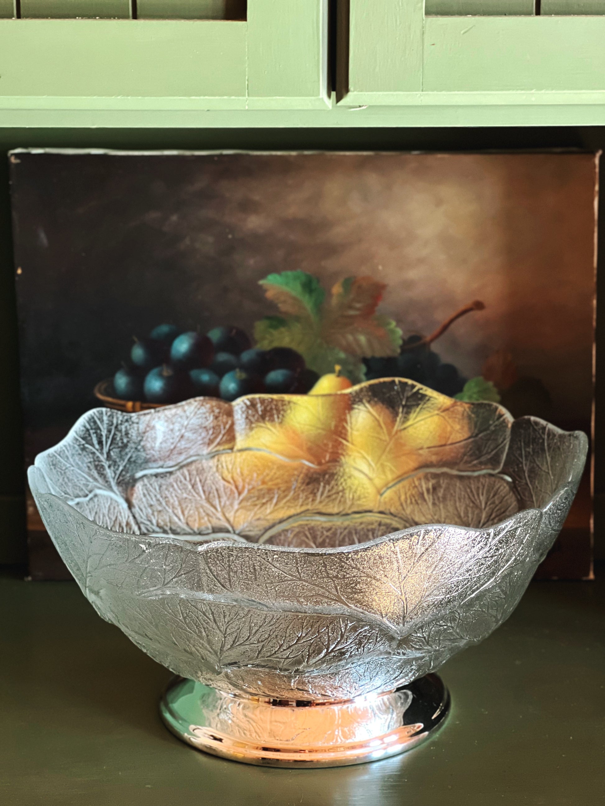 Side view of vintage glass footed centerpiece bowl with textured leaf motif and silver pedestal base