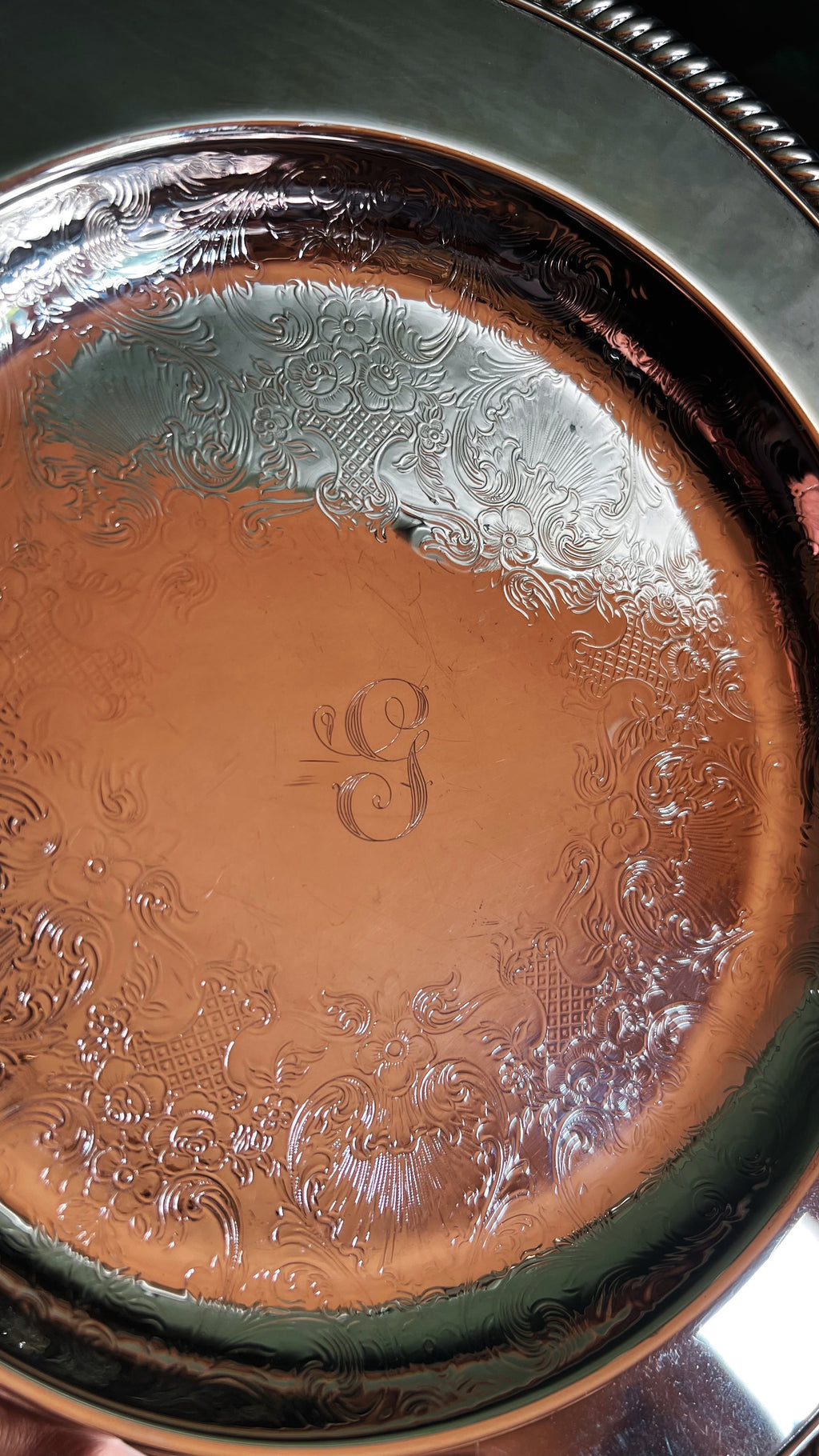 Close-up of a metallic tray with engraved patterns and a visible 'G' monogram.