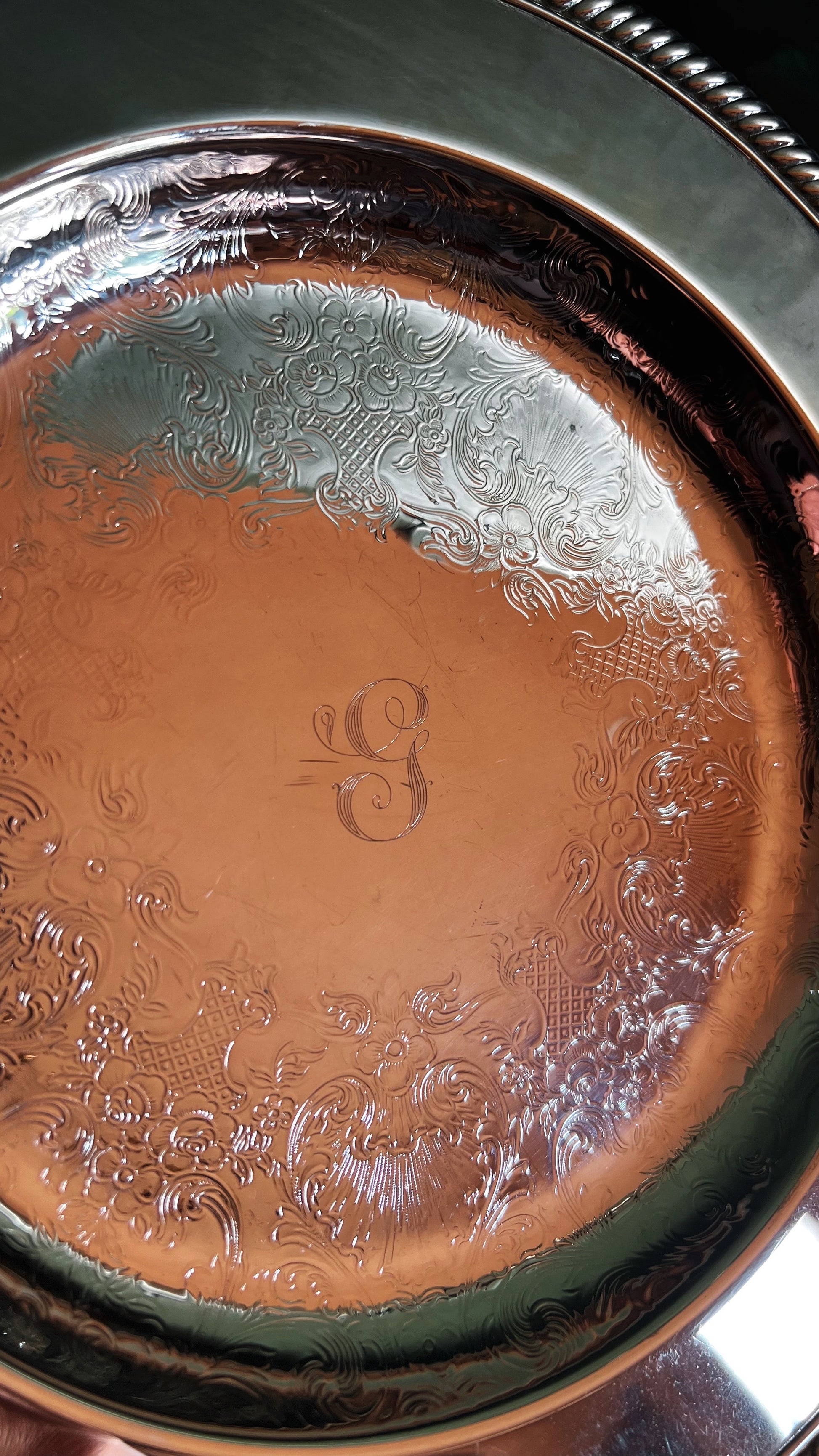 Close-up of a metallic tray with engraved patterns and a visible 'G' monogram.