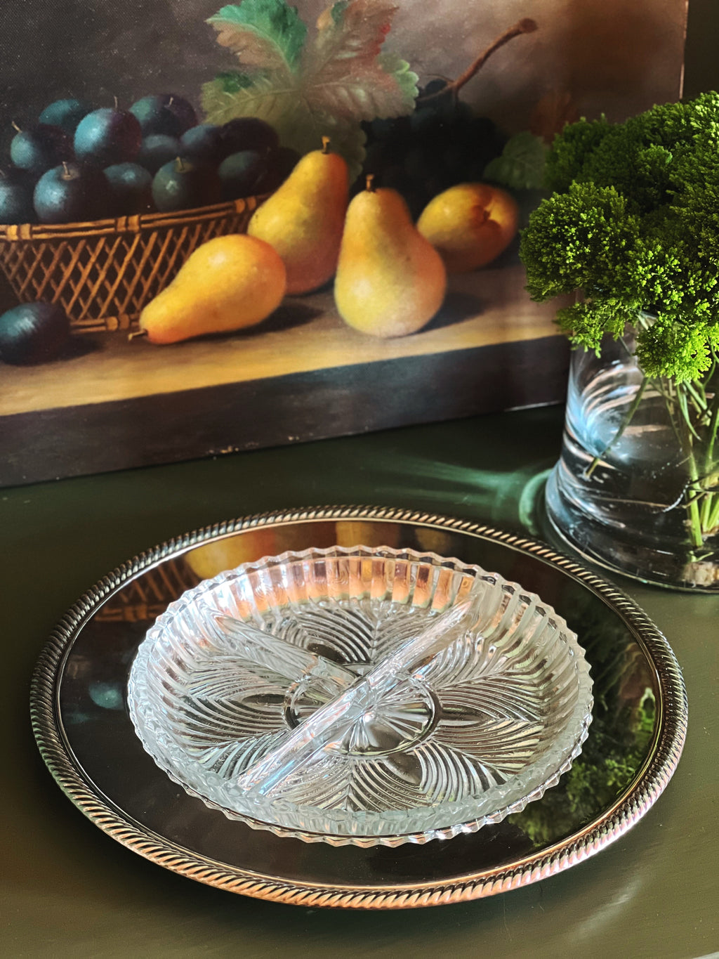 Decorative glass plate on a tray with pears and a painting in the background