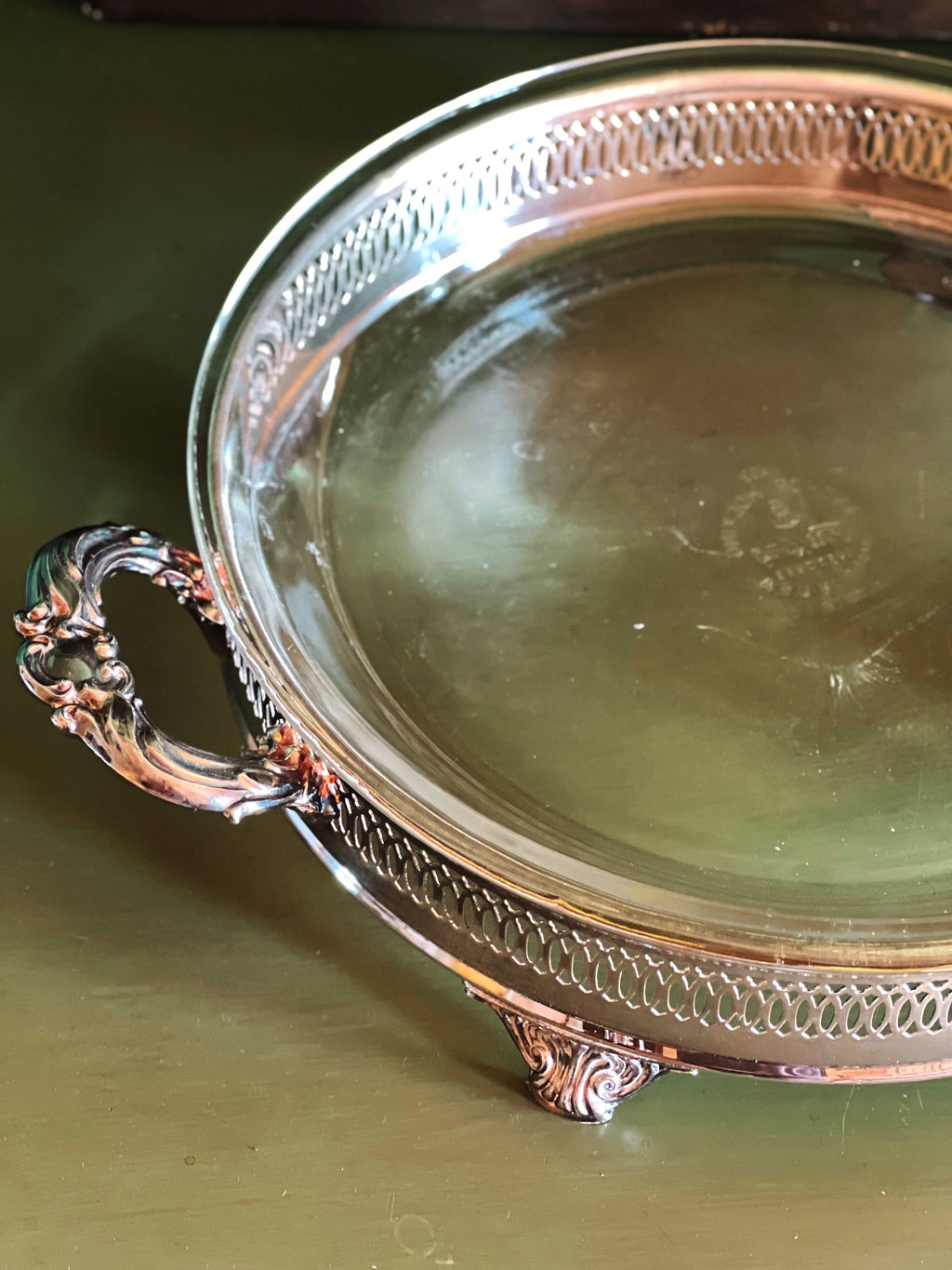 Detail on a silver tray with decorative handles on a green surface