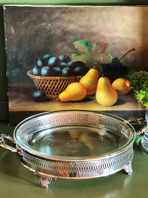 Vintage silverplate casserole server with Fire King glass insert styled with pears and greenery on a dark green surface