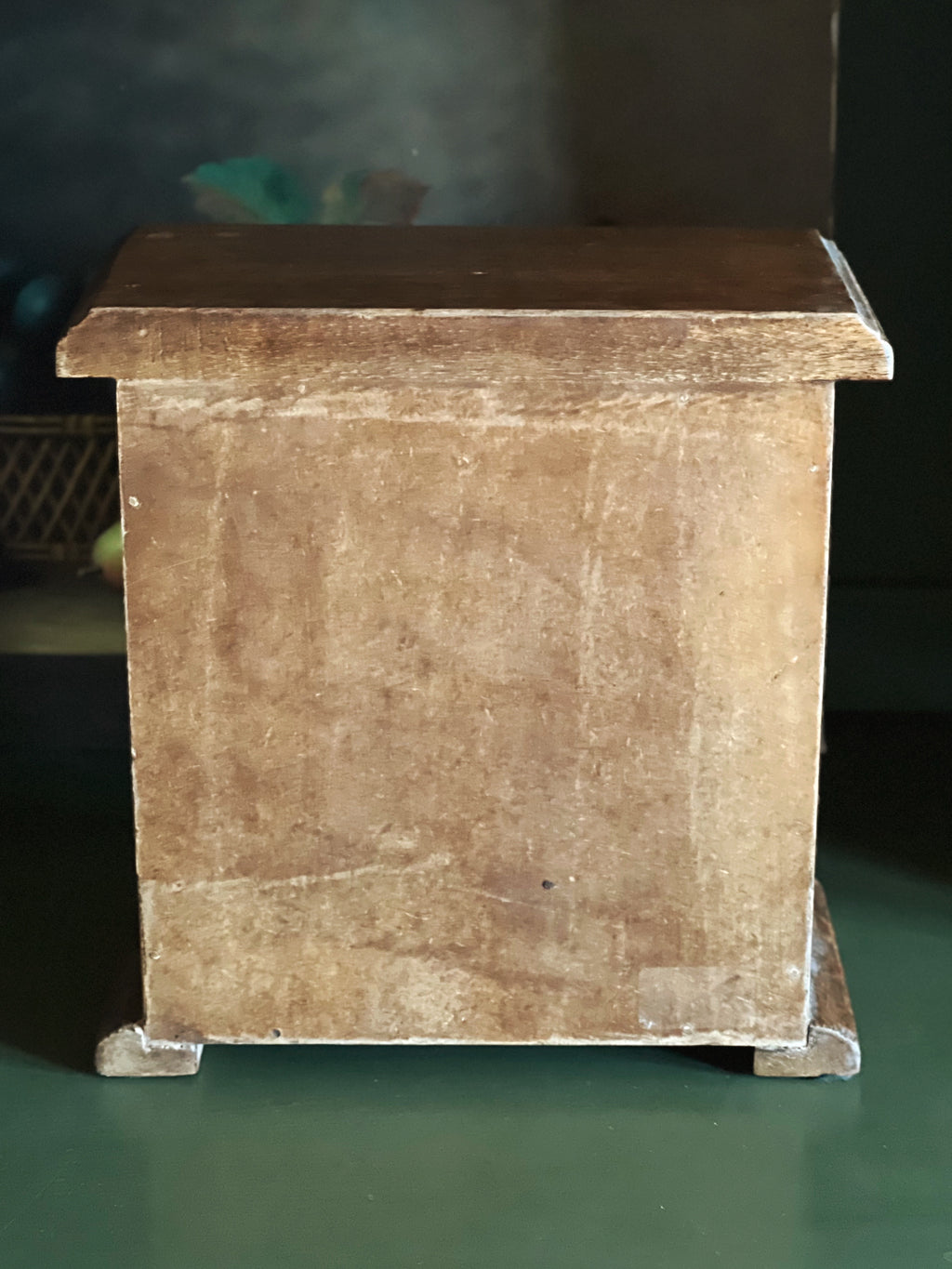 Wooden box with a dark brown top and beige body on a green surface.