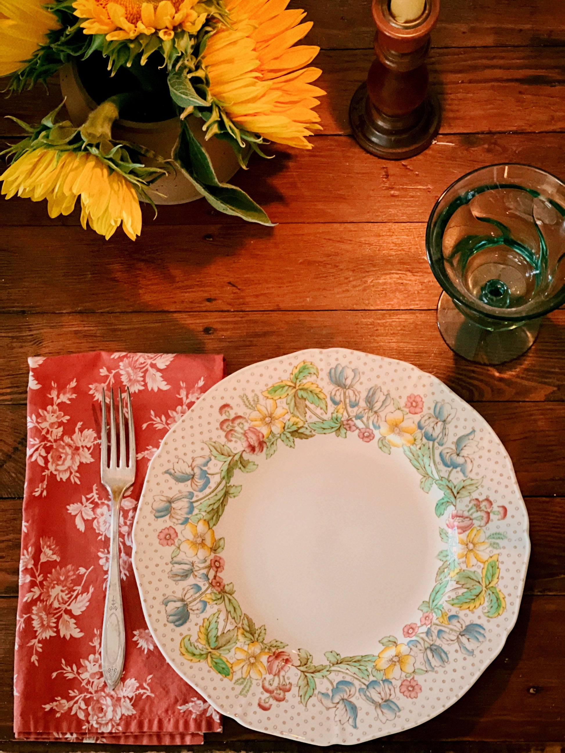 Vintage floral  plate with Williams Sonoma chintz napkins on a wooden table with sunflowers and a glass.