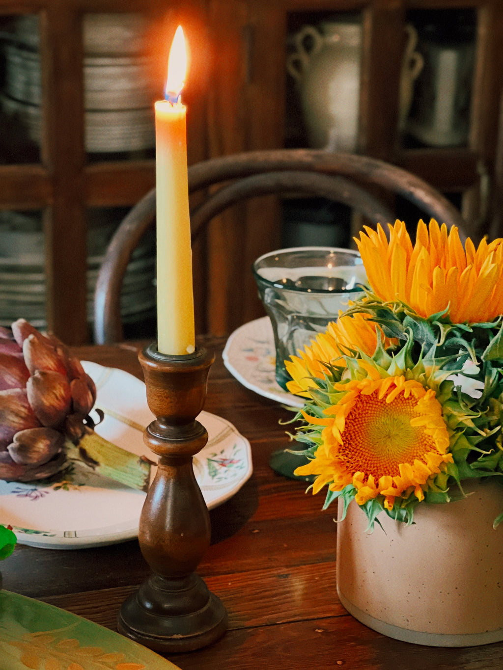 Candle in a wooden holder with sunflowers on a table