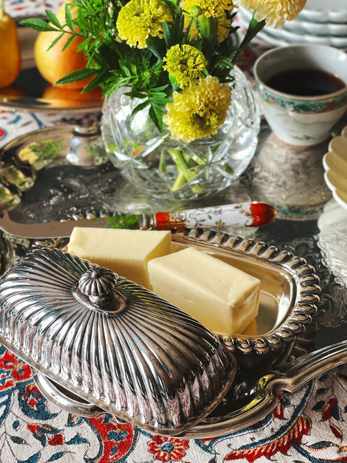 Vintage Crosby silverplate butter dish with lid styled on a breakfast table with butter, flowers, and coffee