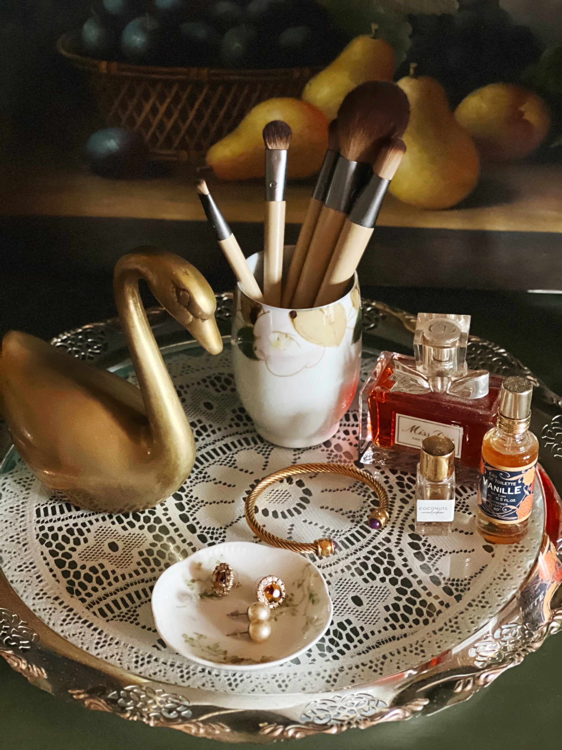 Vintage brass swan on tray with makeup brushes and perfume bottles