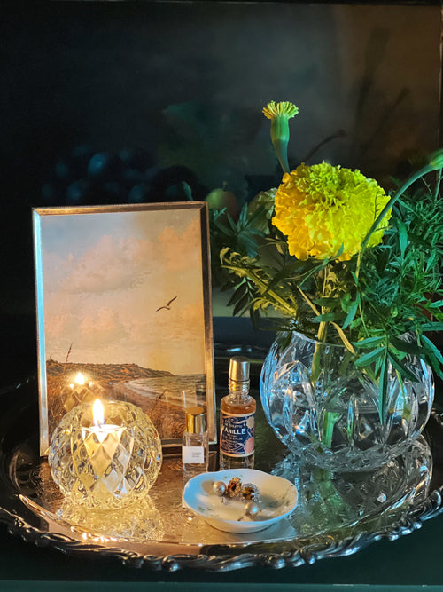 Tray with a candle, bottle, and vase of flowers on a dark background