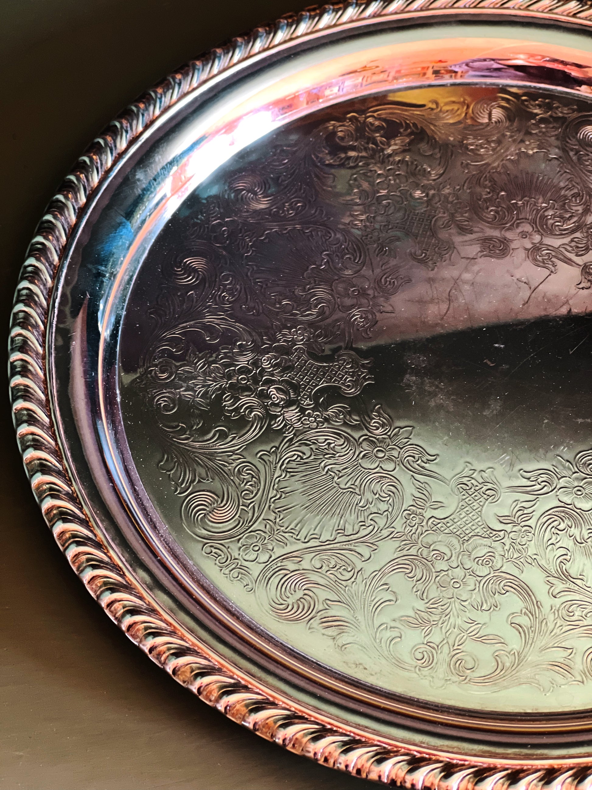 rope edge detail of a decorative silver tray with intricate patterns on a dark surface