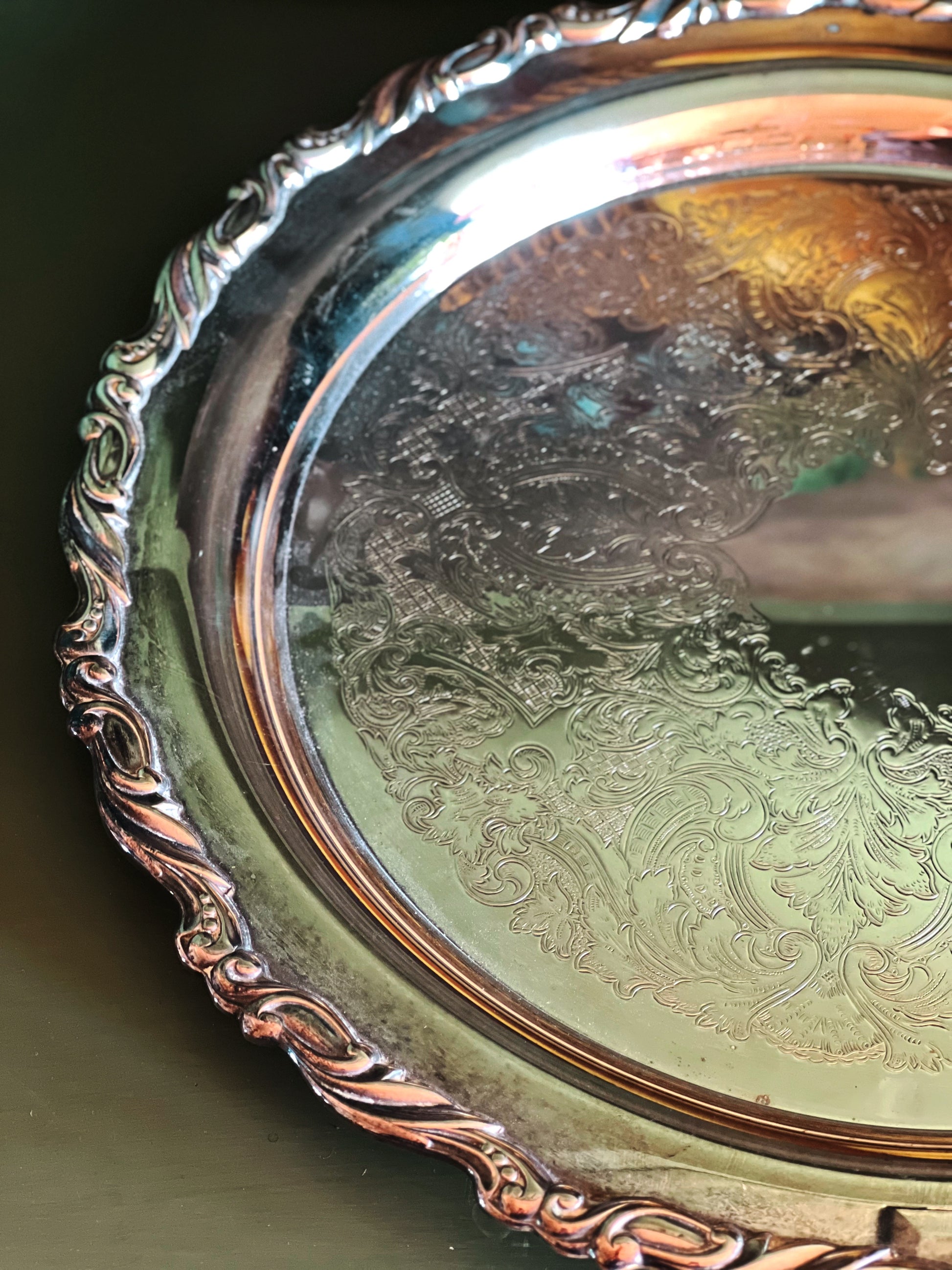 Close up of a vintage silver tray with a decorative scrollwork edge