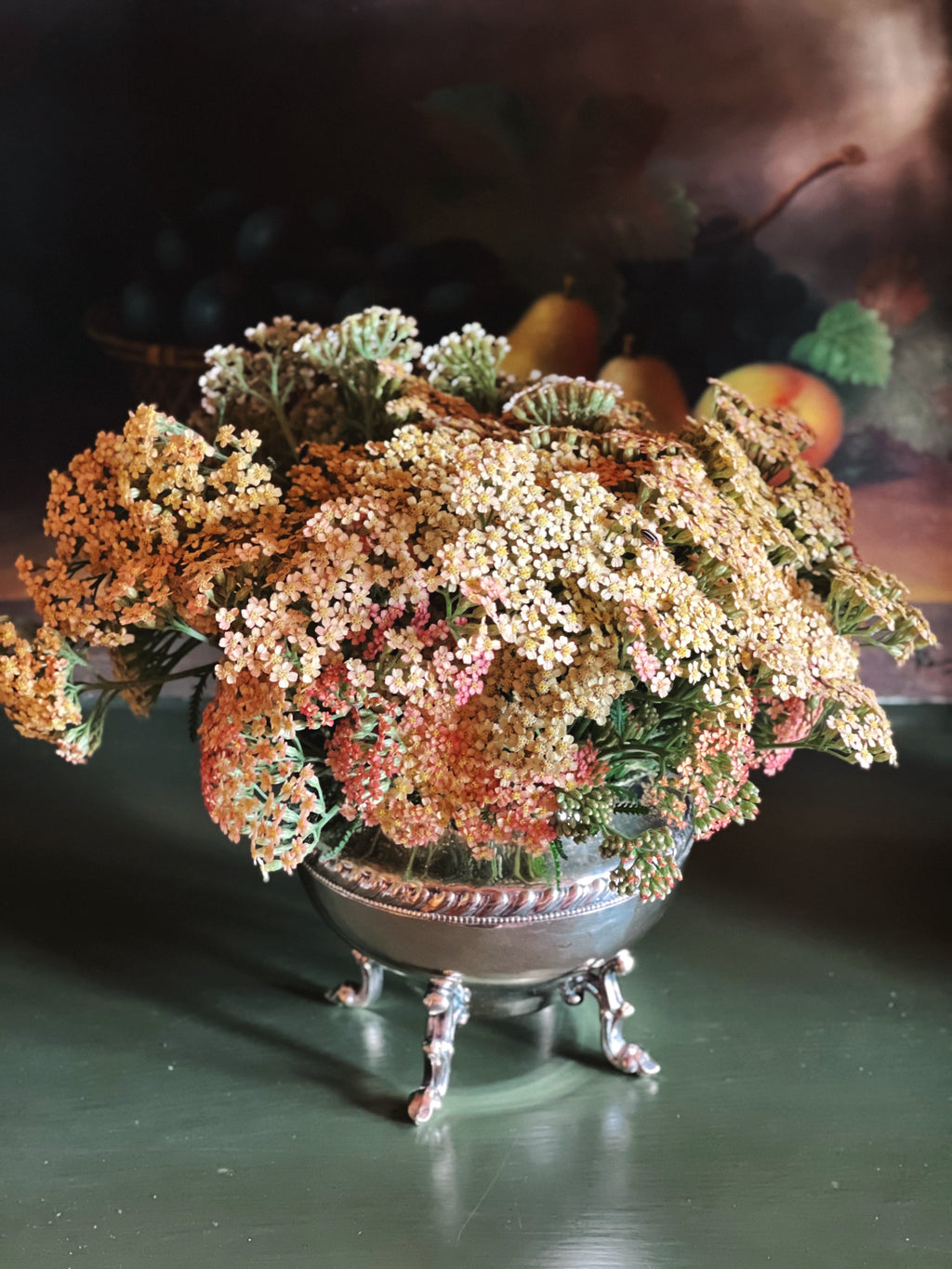Decorative floral arrangement in a silver bowl on a dark surface