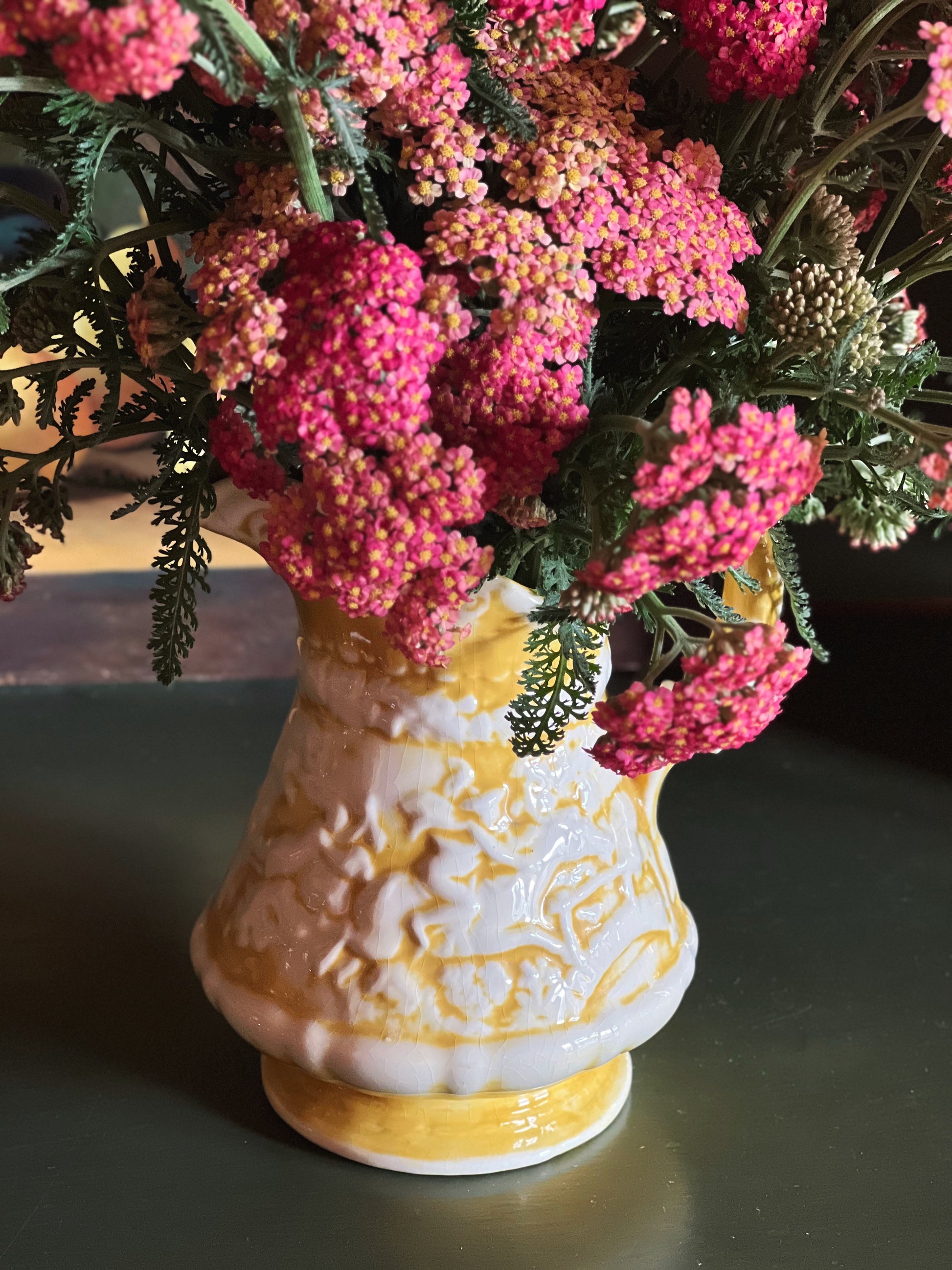 Handmade vintage yellow ceramic pitcher filled with pink yarrow flowers 