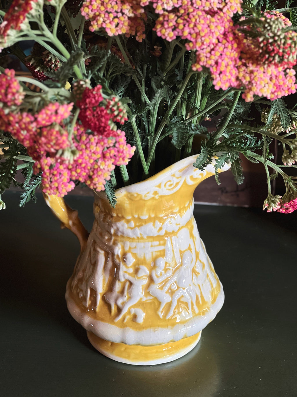 Decorative yellow vase with floral arrangement on a dark surface