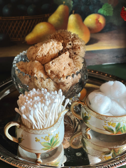 Antique hand-painted Nippon creamer and sugar bowl with yellow floral details styled with cotton balls and cotton swabs on a silver tray