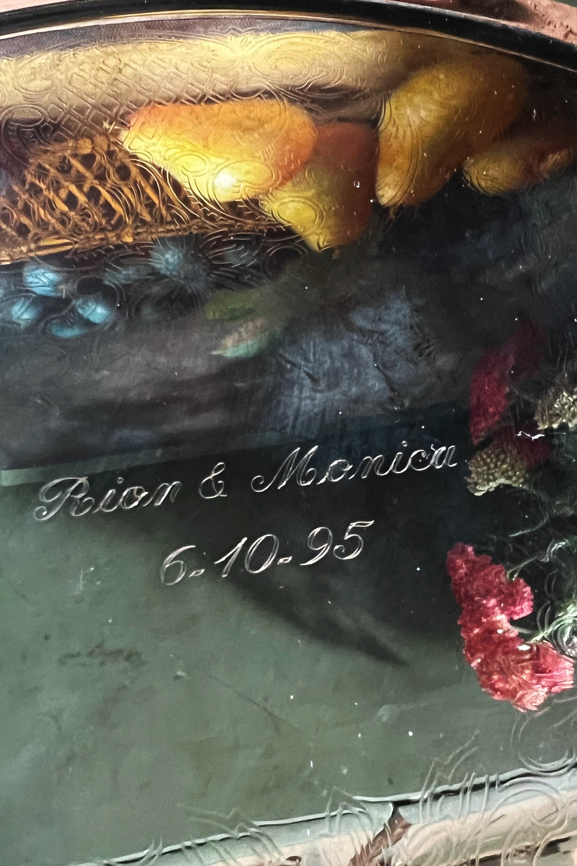 Decorative glass item with engraved names and date, featuring flowers and a textured surface.