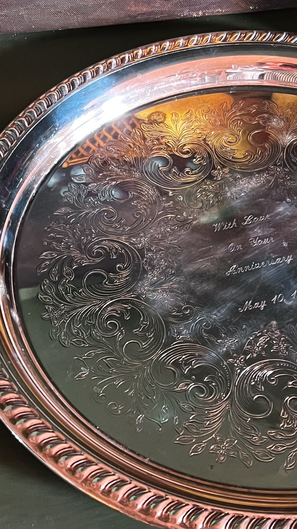 Decorative silver tray with intricate engravings and text on a dark surface