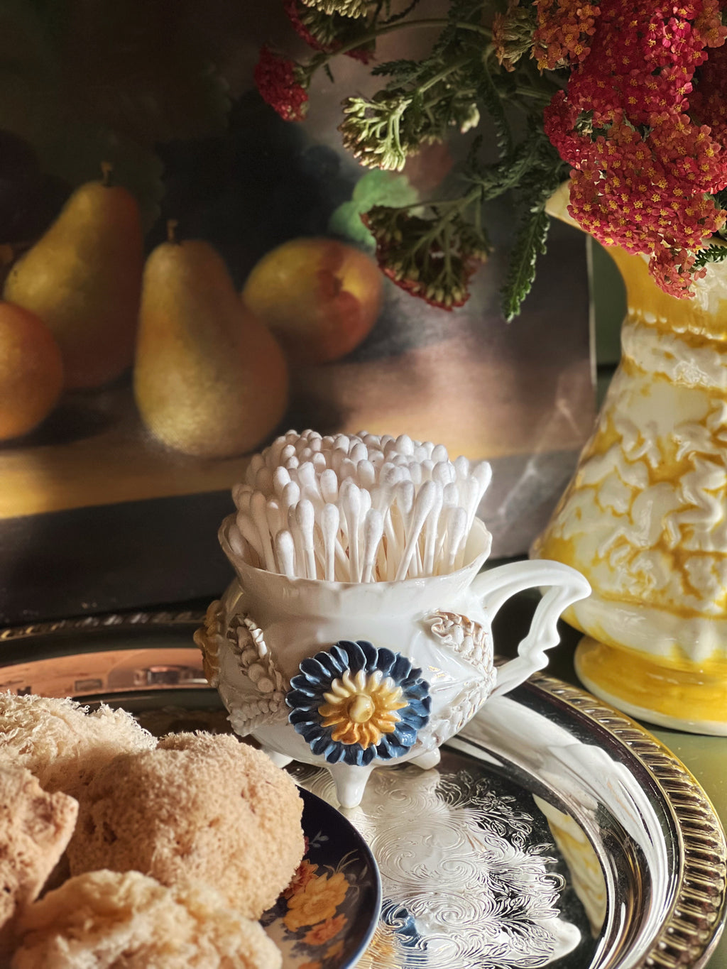 Decorative table setting with teacup, flowers, and sea sponges on a tray.