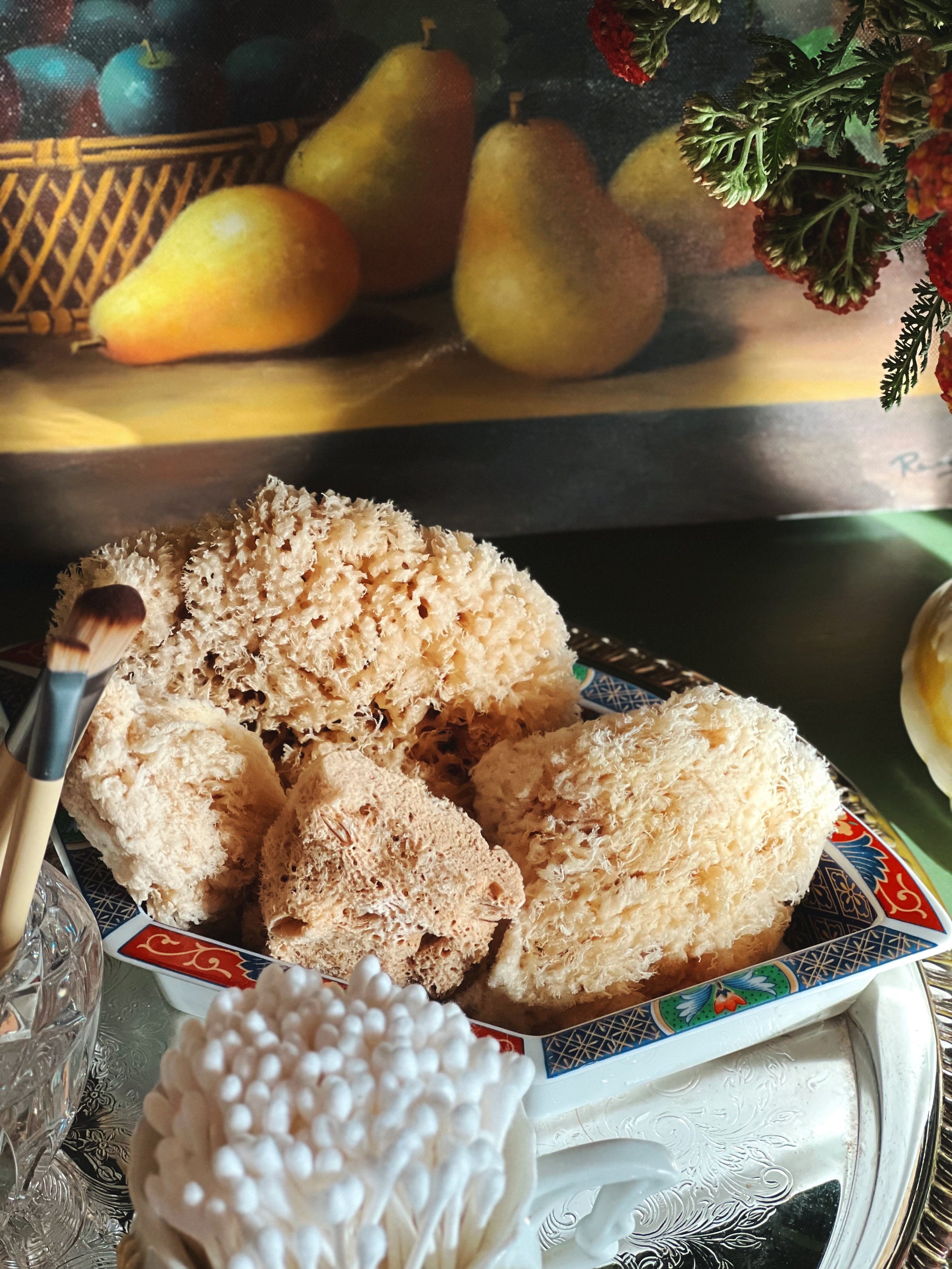 Decorative display with textured spherical objects, pears, and a painting in the background.
