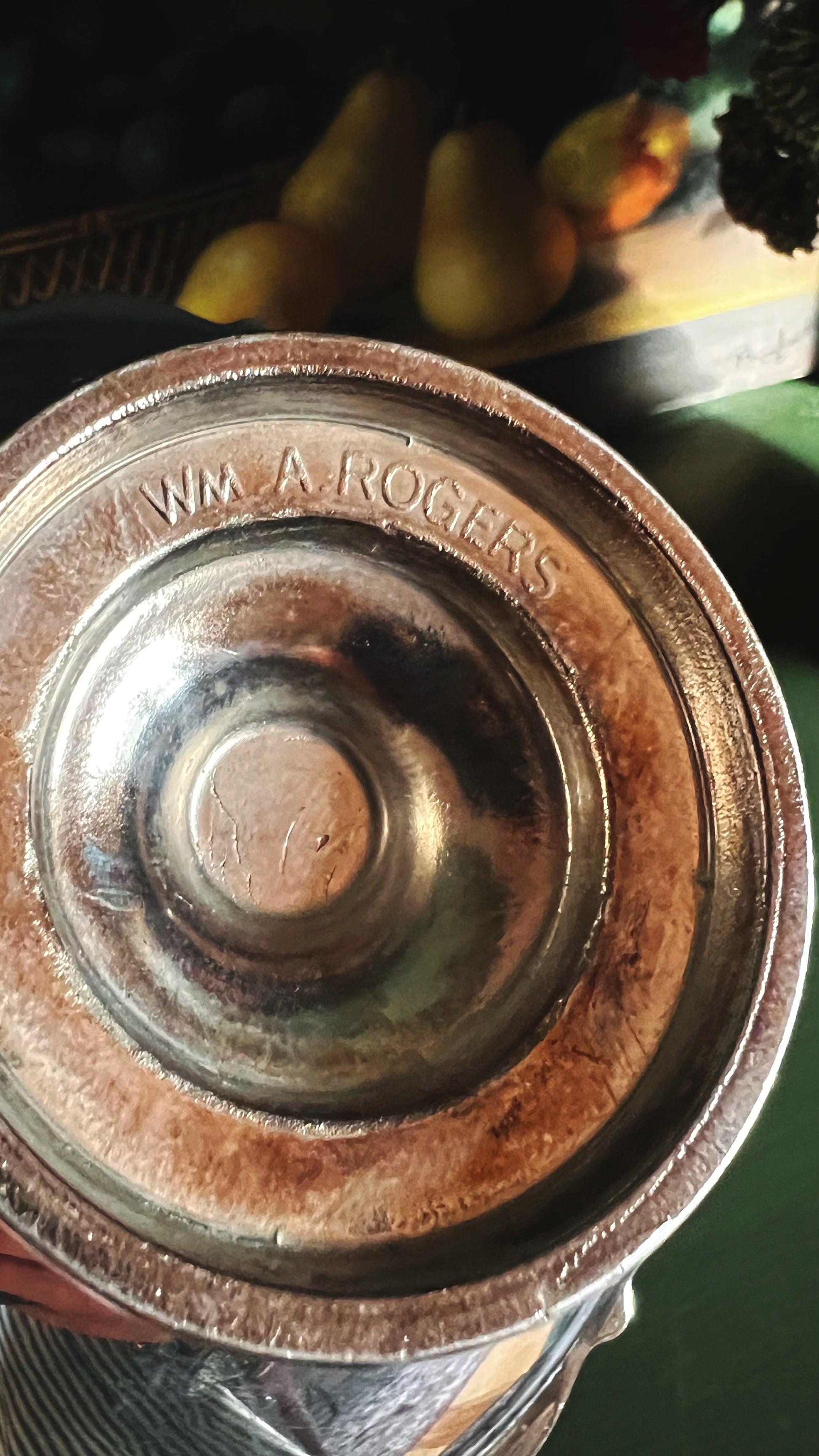 Close-up of a silver compote with 'WM A Rogers' engraving, blurred background