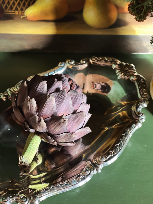 Artichoke on a decorative silver platter with a blurred background