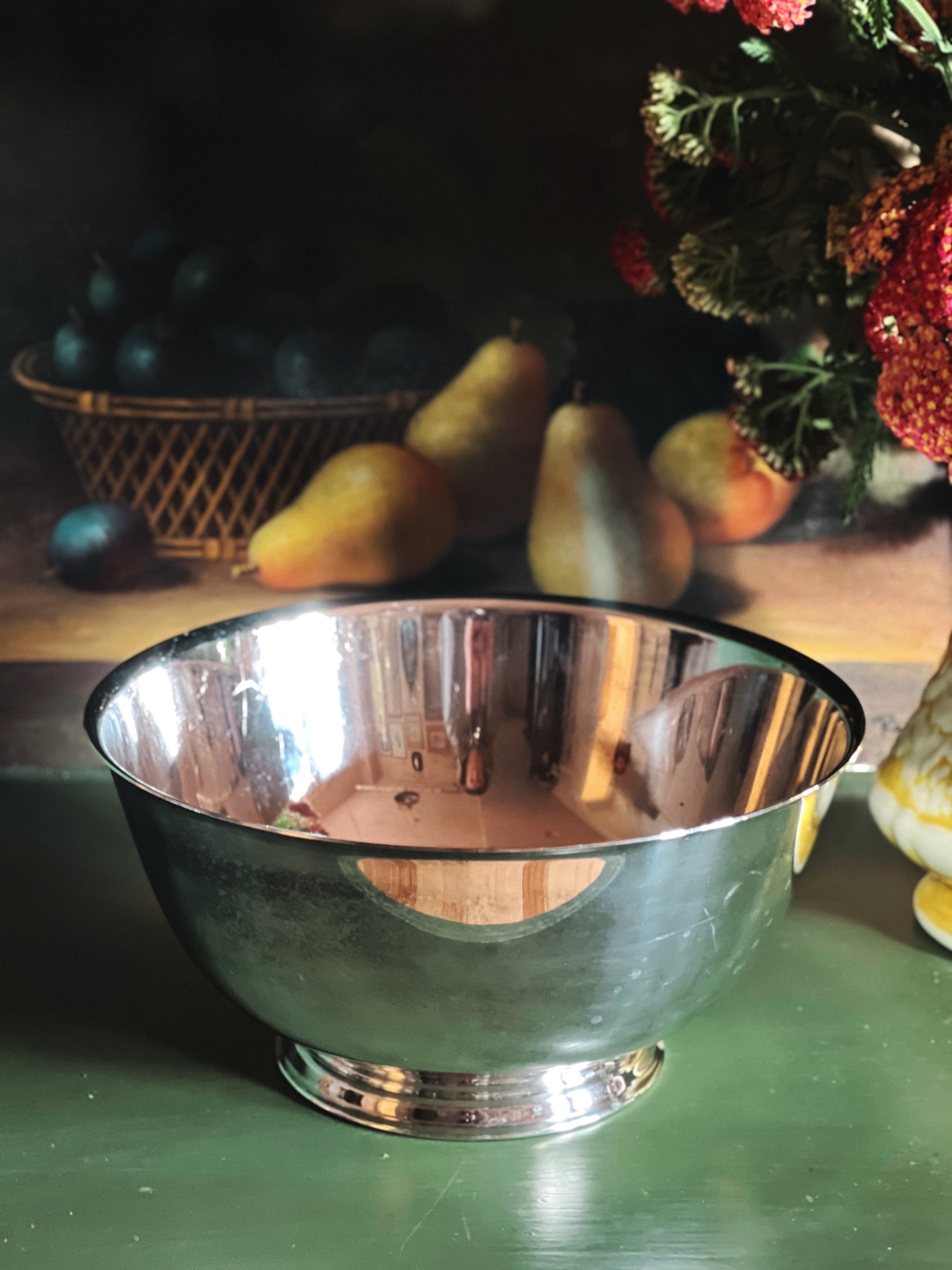 Oneida Paul Revere silver bowl on a green surface with fruits and a basket in the background