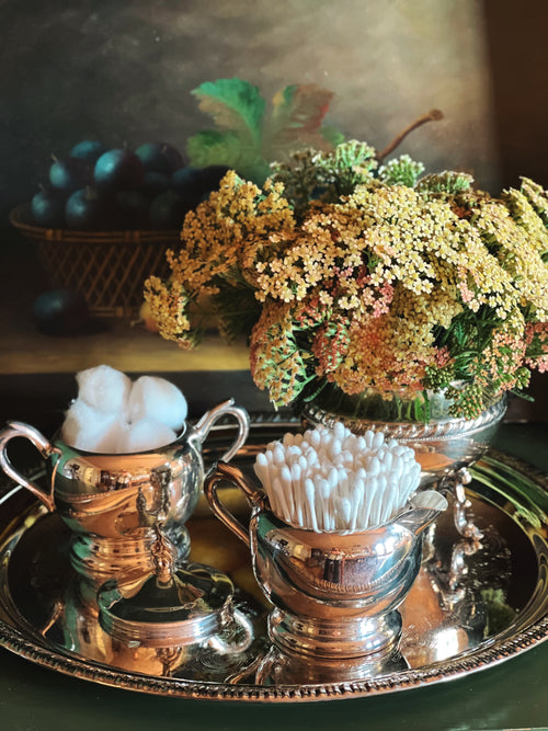Silver containers with cotton balls on a reflective surface