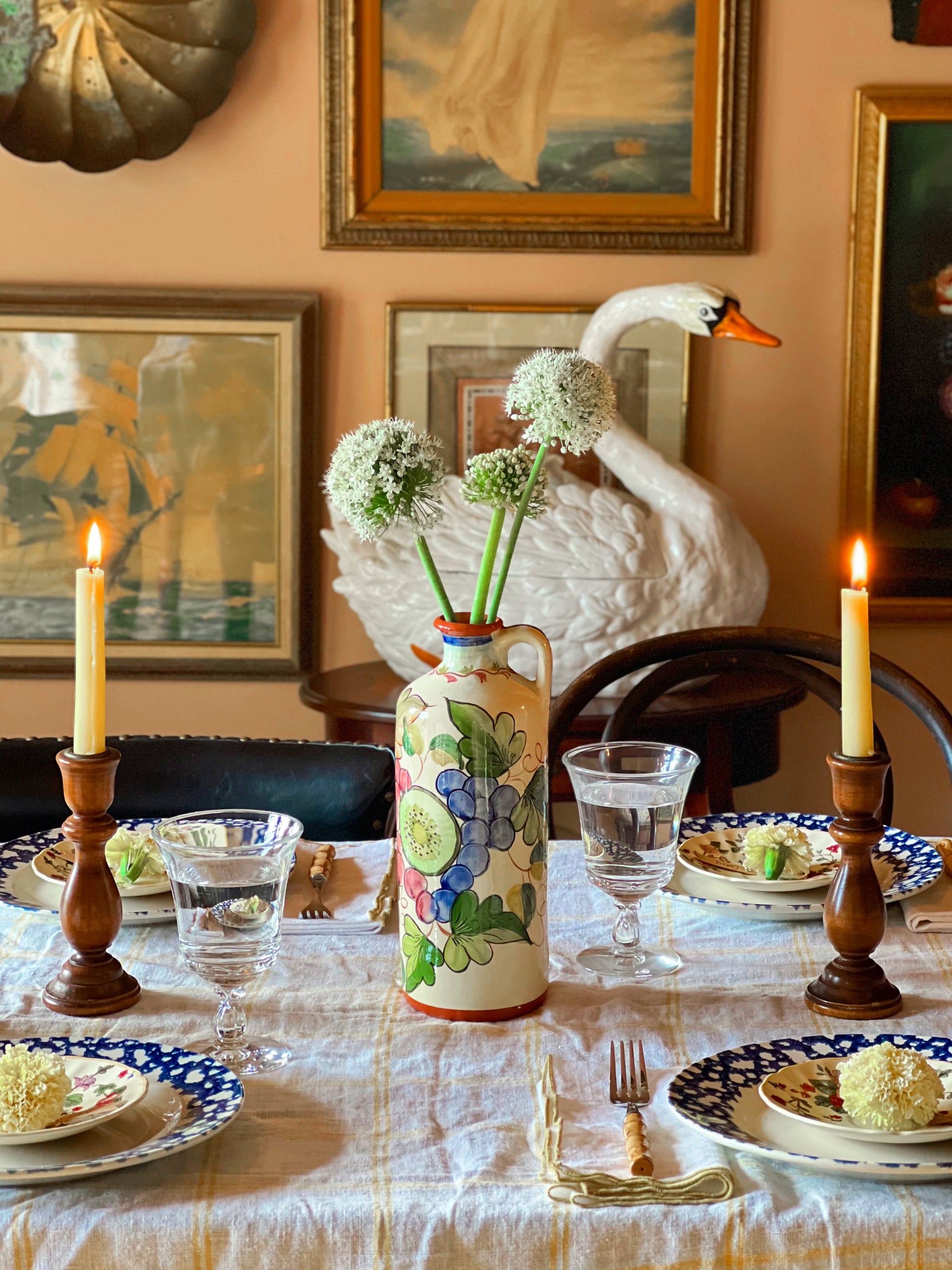 Dining table set with floral arrangements, candles, and a decorative swan sculpture.