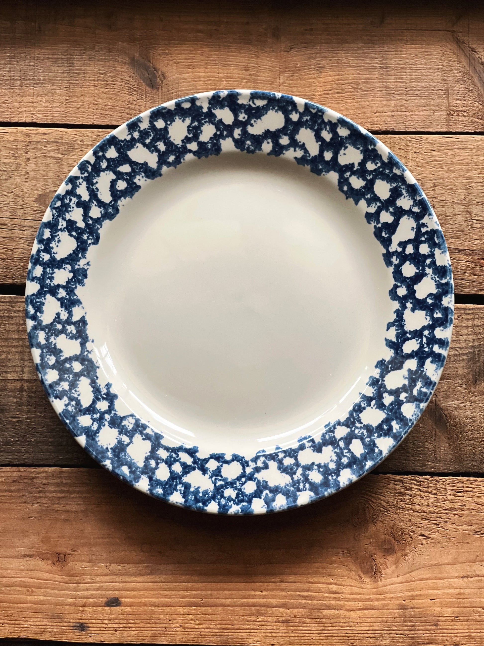 navy spongeware pattern dinner plate on a wooden surface
