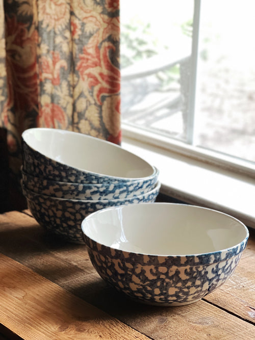 Set of blue and white patterned bowls on a wooden surface with a window in the background.