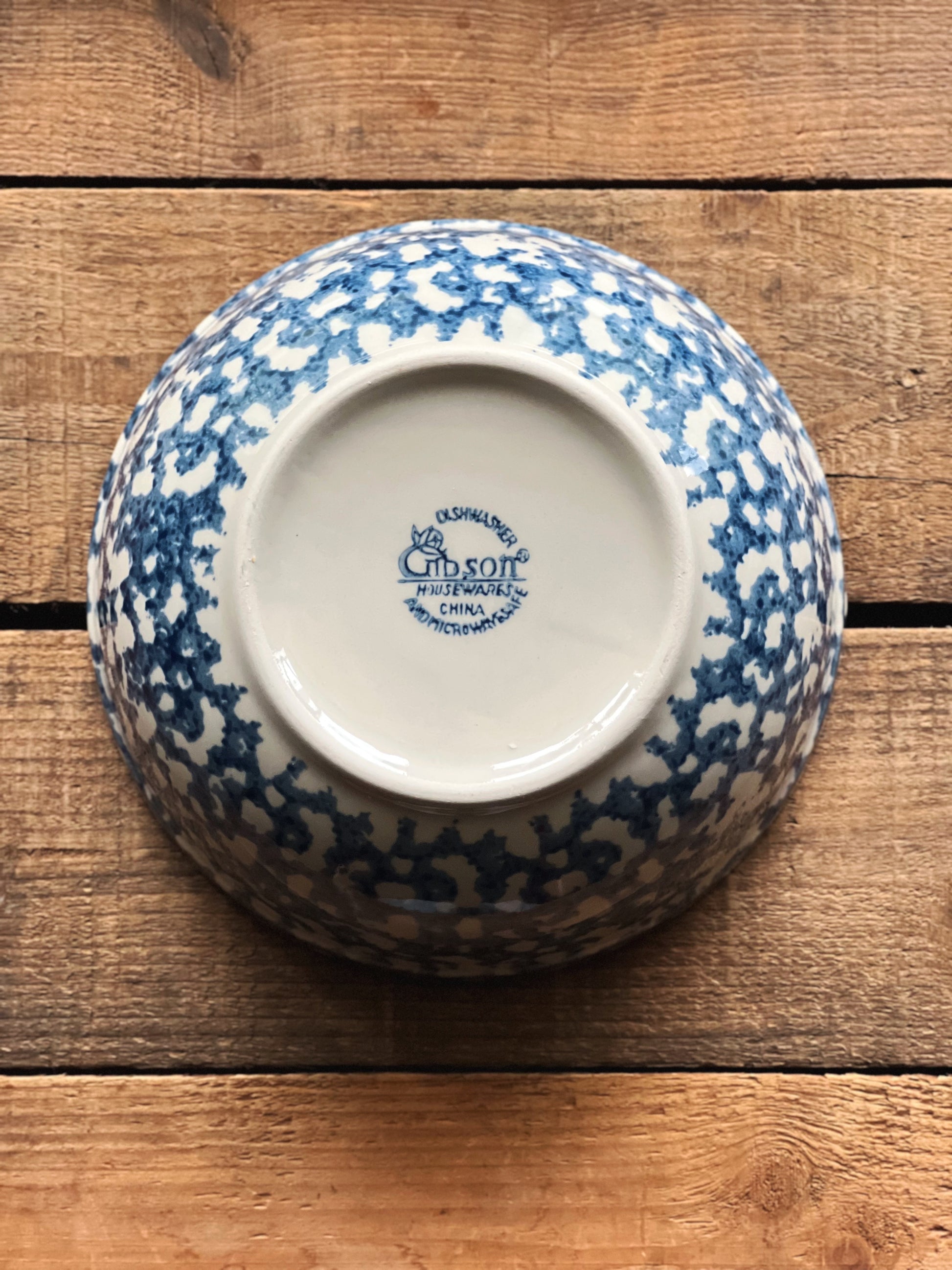 Blue and white stoneware bowl with a Gibson brand logo on a wooden surface