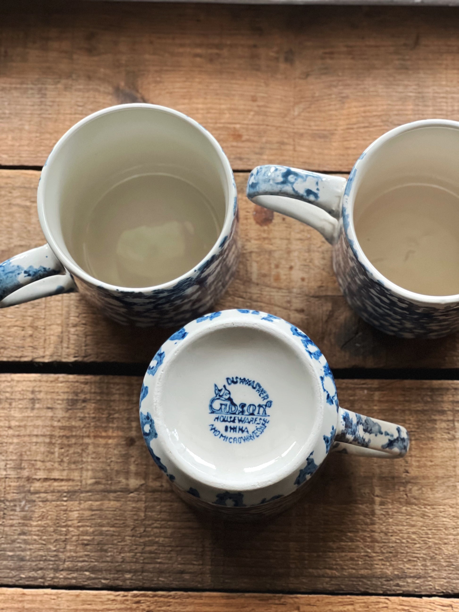 Three Gibson stoneware mugs with blue patterns on a wooden surface