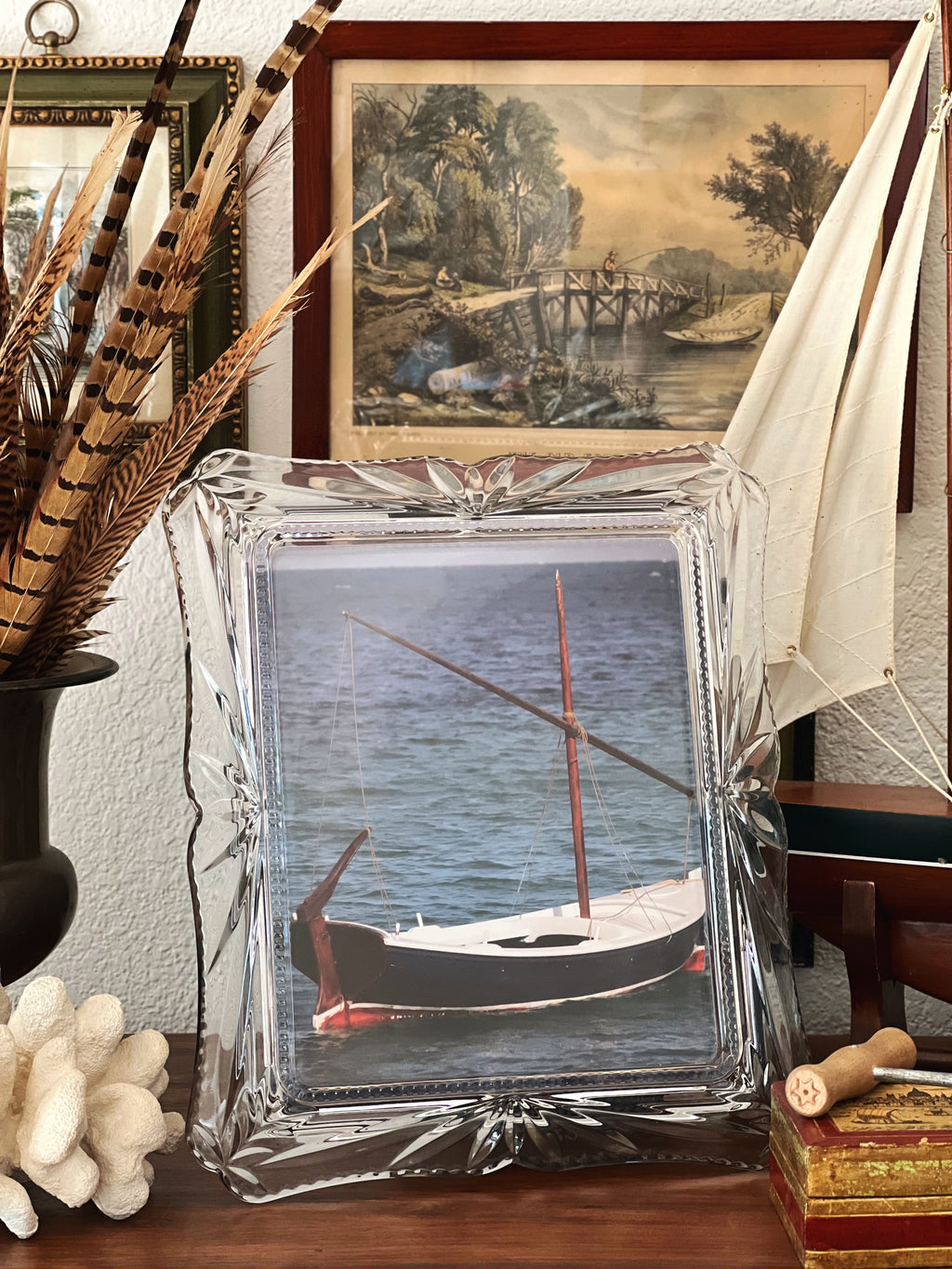Decorative crystal frame with a photo of a boat on a table with decorative items.