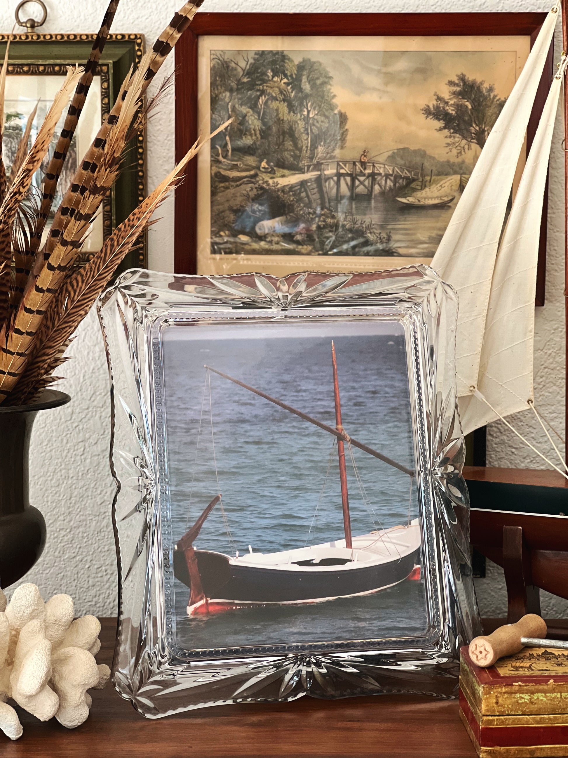 Decorative crystal frame with a photo of a boat on a table with decorative items.