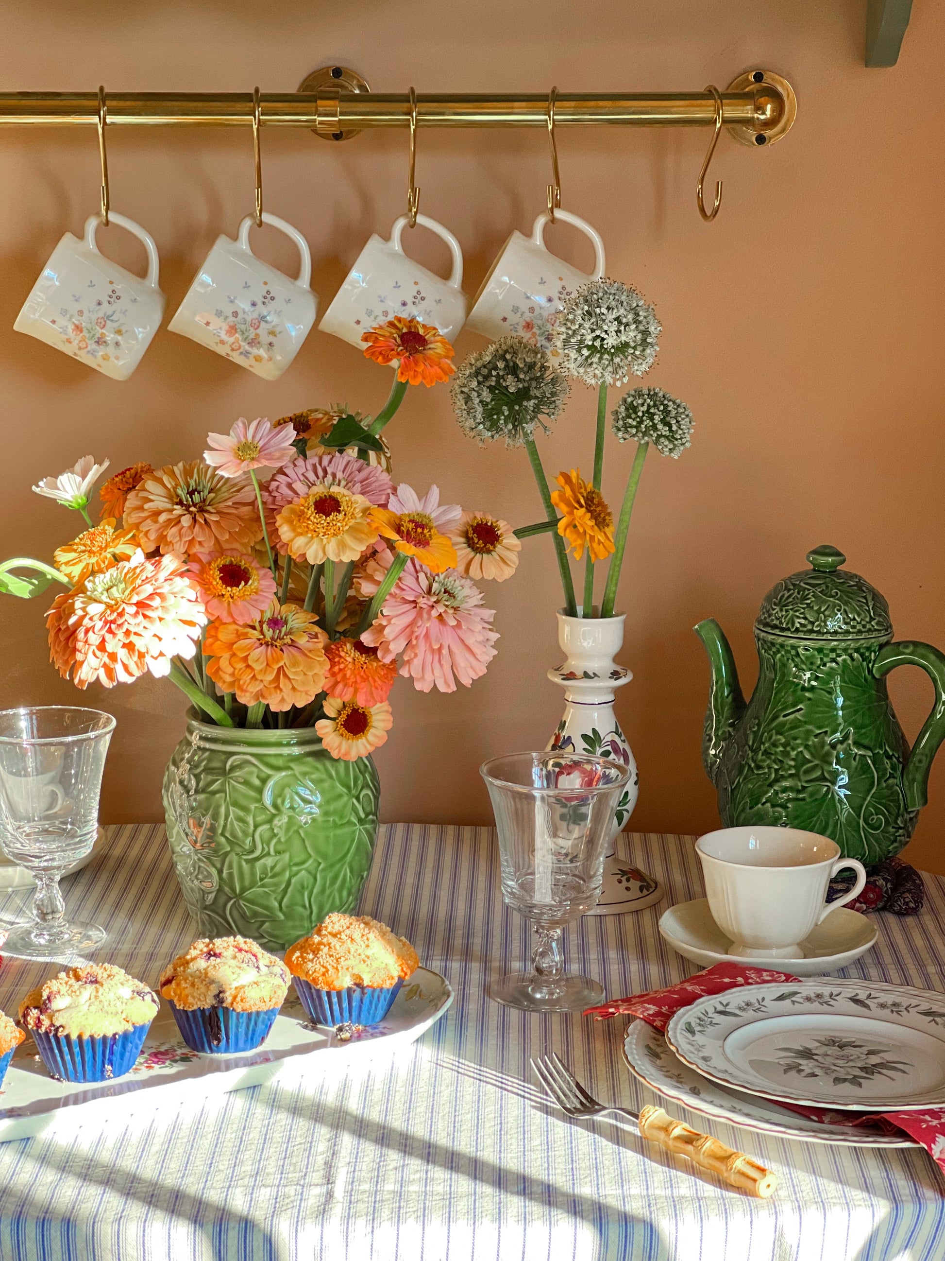Dining table setting with floral arrangements, teapot, and muffins.