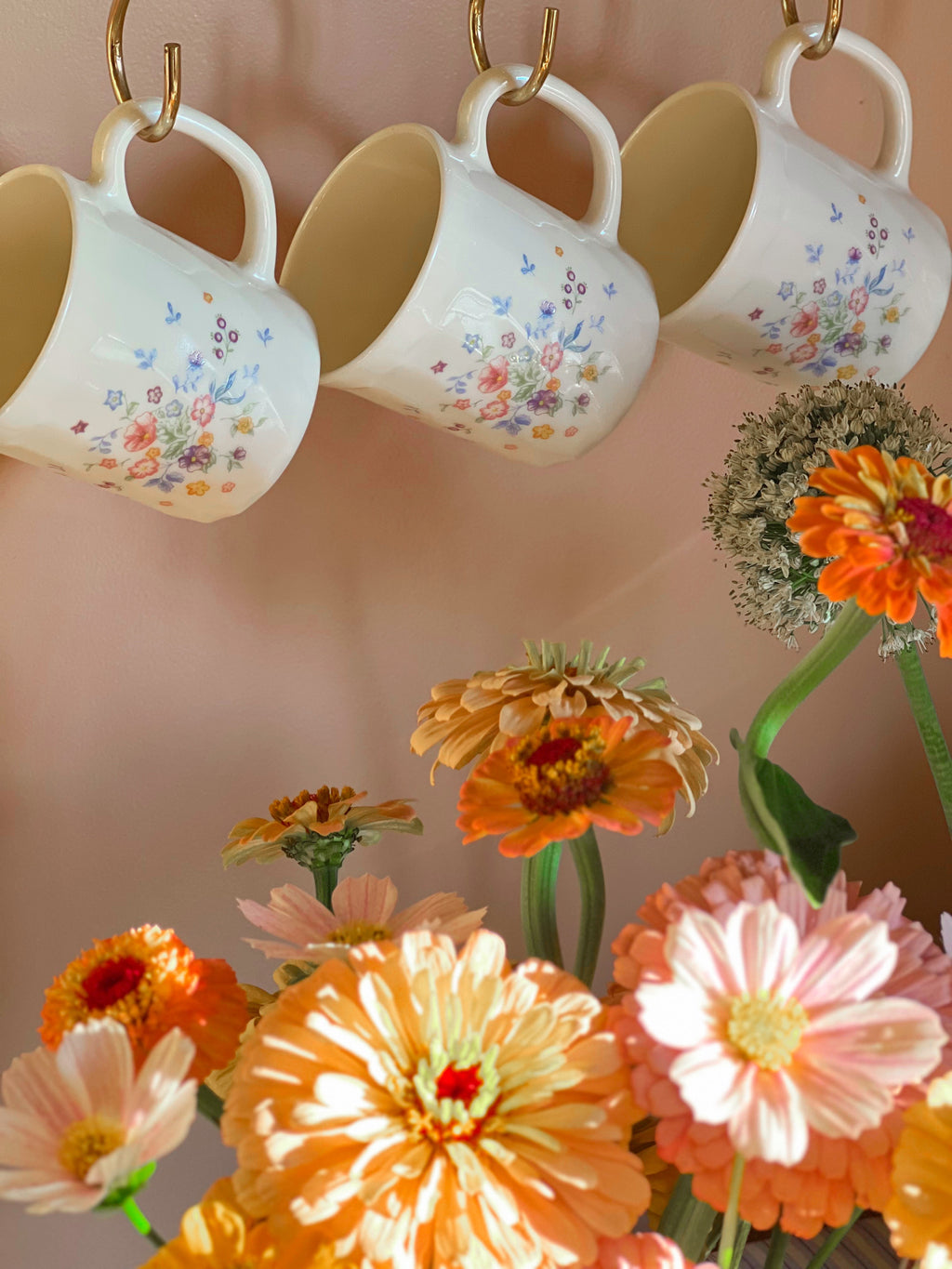 Arcopal Victoria floral mugs hanging on hooks above a flower arrangement