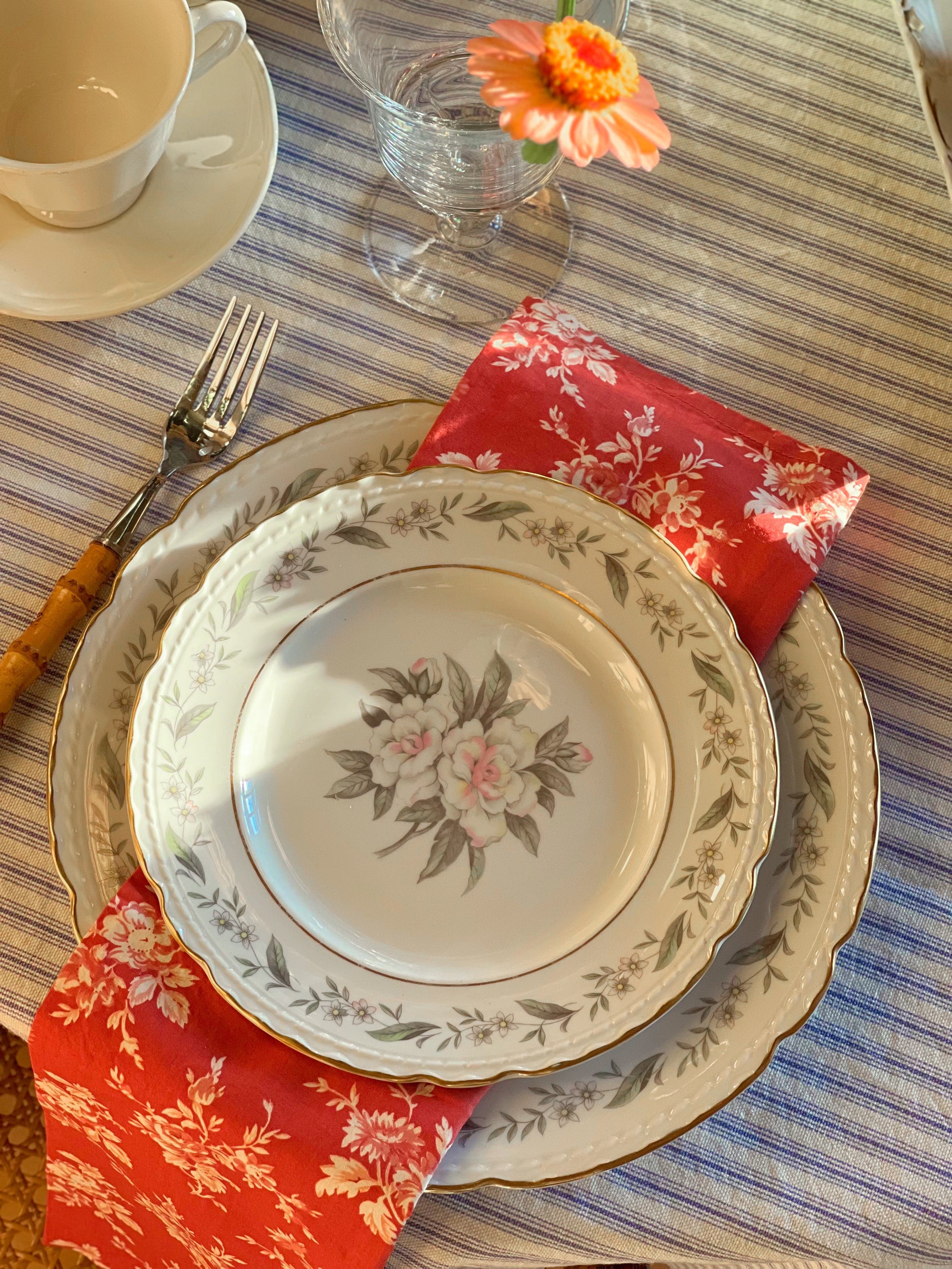 Royal Jackson Fleur De Blanc plates layered on a table with floral napkins and a striped tablecloth