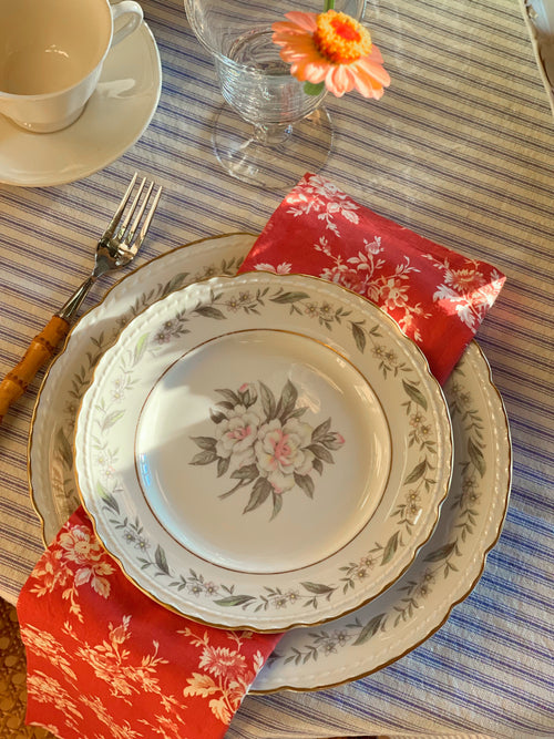 Royal Jackson Fleur De Blanc plates layered on a table with floral napkins and a striped tablecloth
