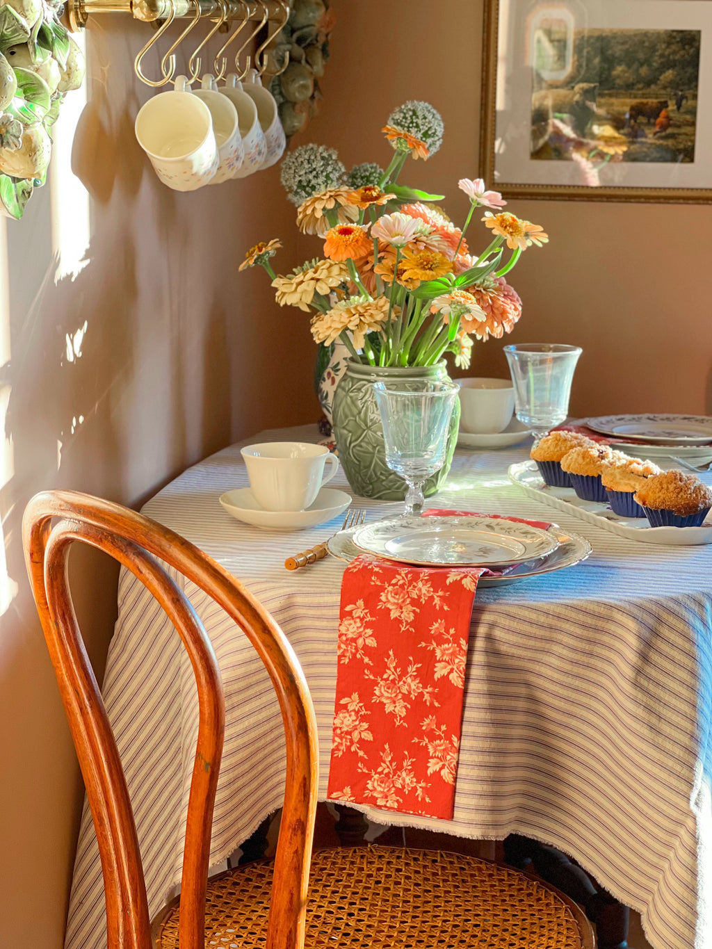 Dining table set with flowers, plates, and a chair in a cozy room.